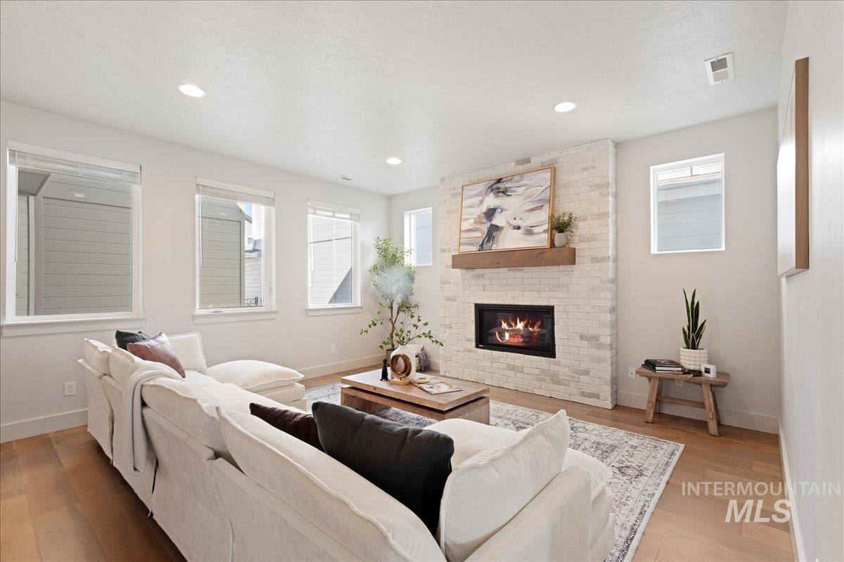 Living area with wood finished floors, a fireplace, a textured ceiling, and recessed lighting