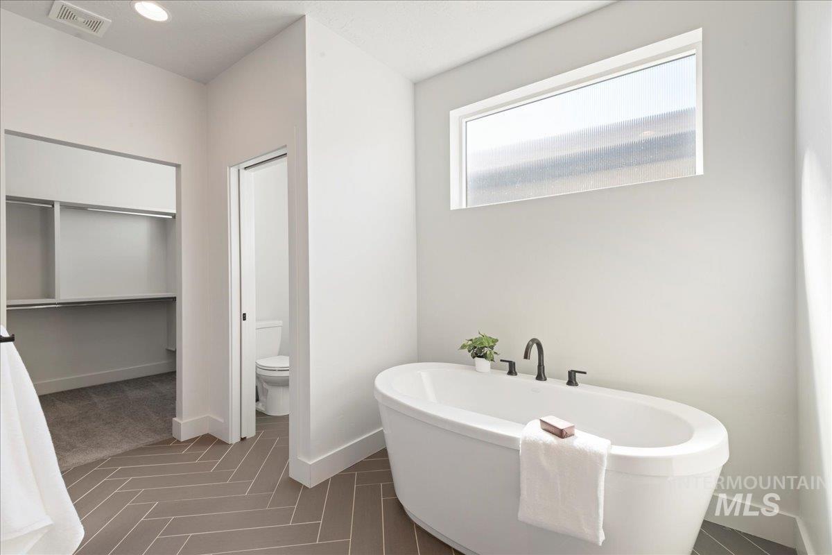 Bathroom featuring a freestanding tub, a walk in closet, and recessed lighting