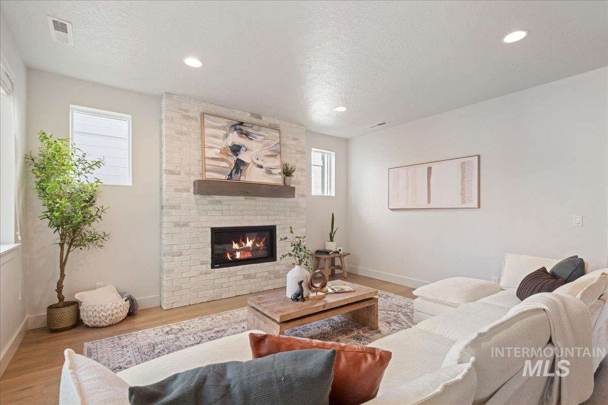 Living area with wood finished floors, a fireplace, a textured ceiling, and recessed lighting
