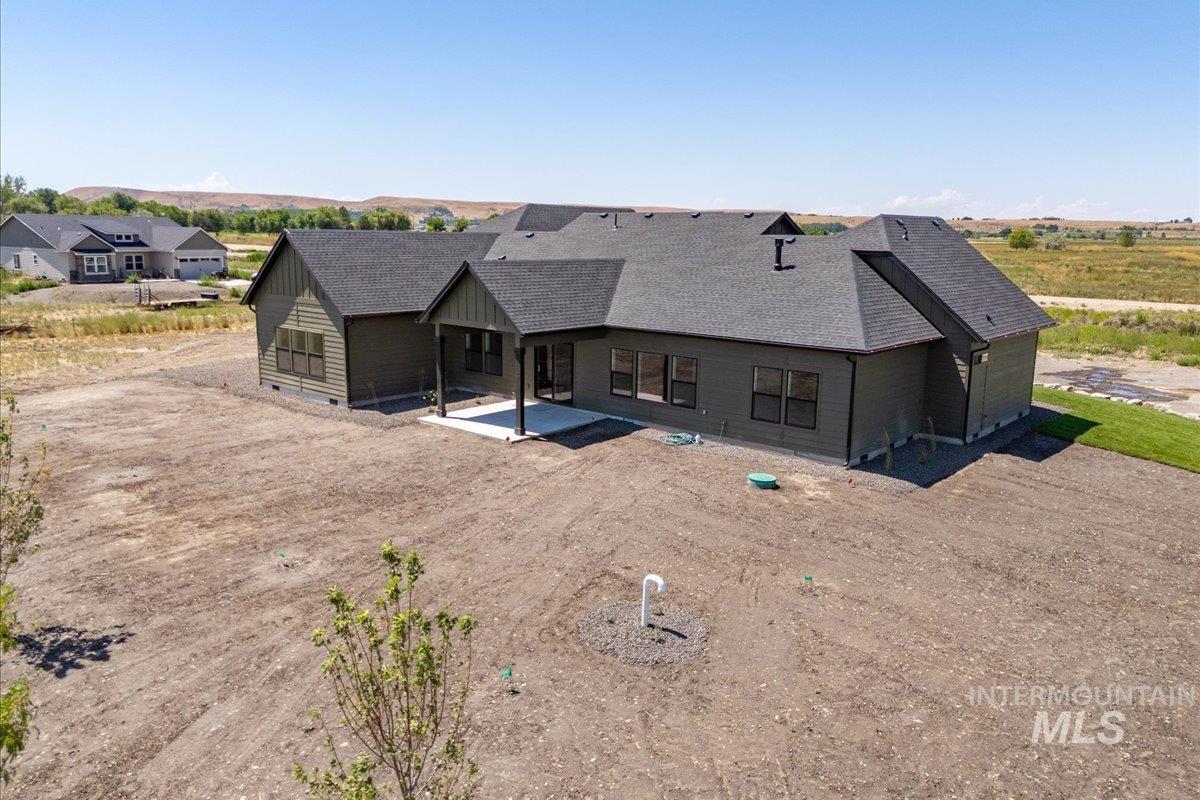 Back of house with a patio area and roof with shingles