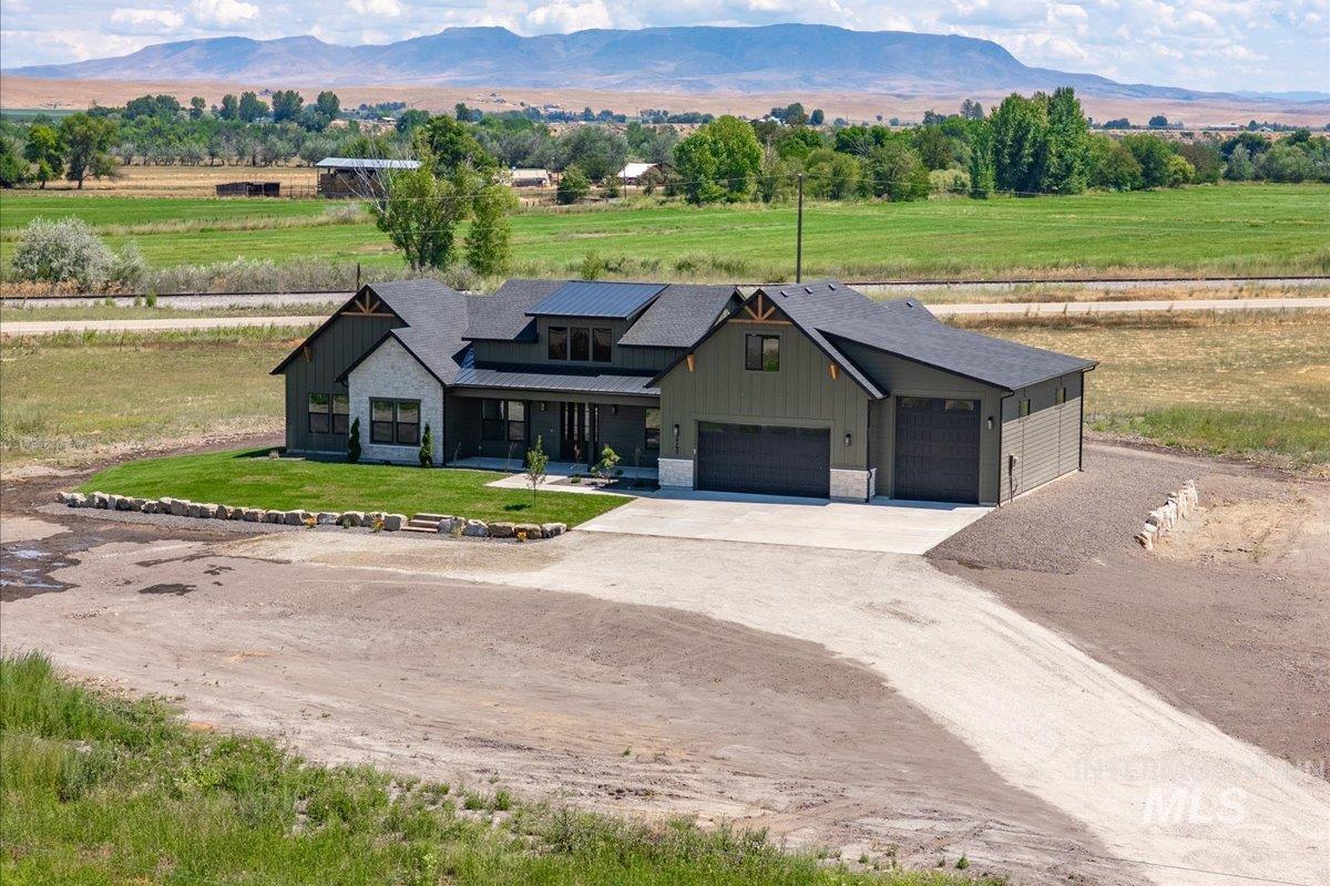 Modern farmhouse with dirt driveway, a metal roof, a mountain view, and board and batten siding