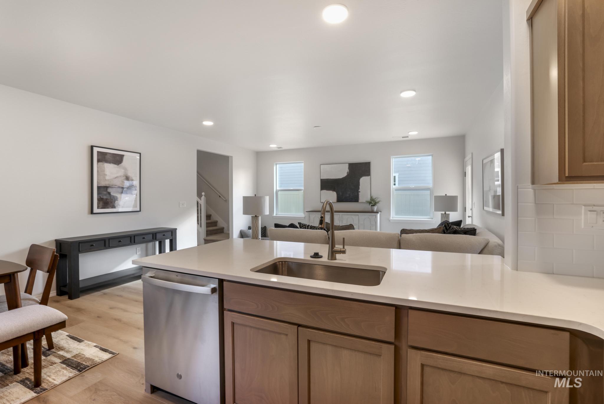 Kitchen featuring open floor plan, dishwasher, light wood finished floors, a peninsula, and recessed lighting