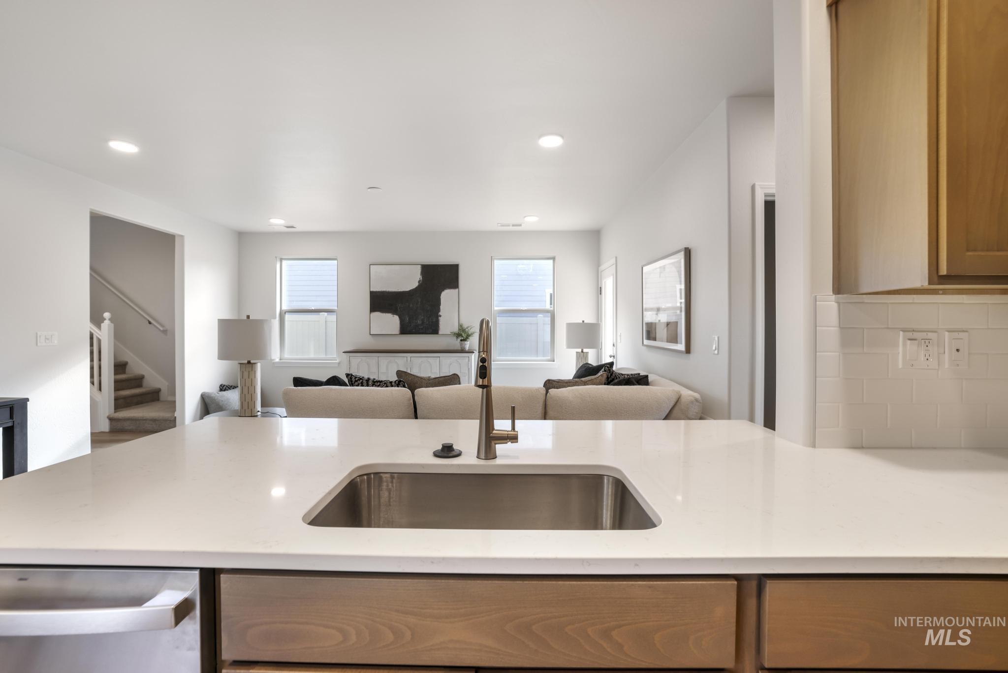 Kitchen featuring stainless steel dishwasher, light stone countertops, open floor plan, recessed lighting, and a peninsula