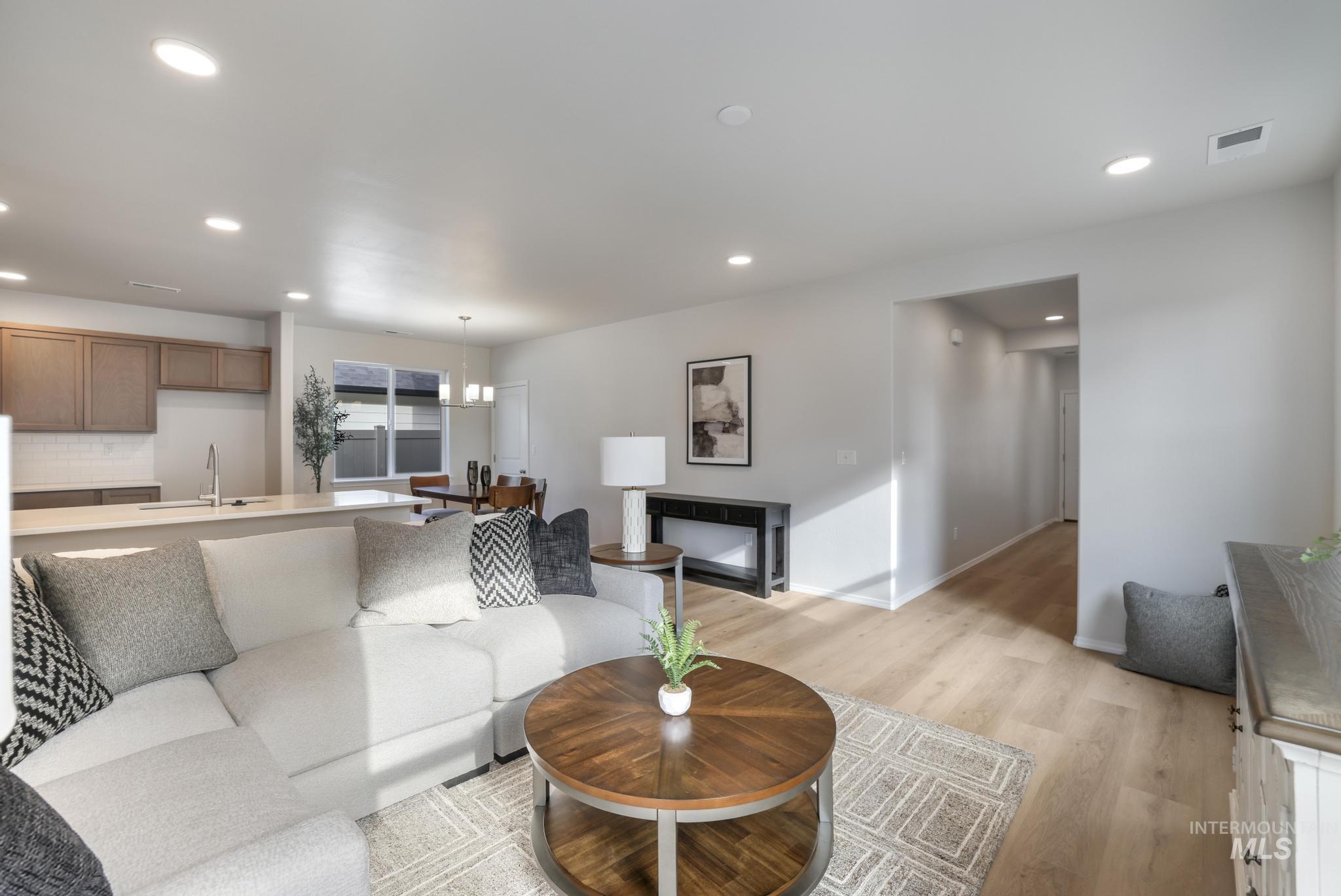 Living area with light wood-style floors, recessed lighting, a chandelier, and a fireplace