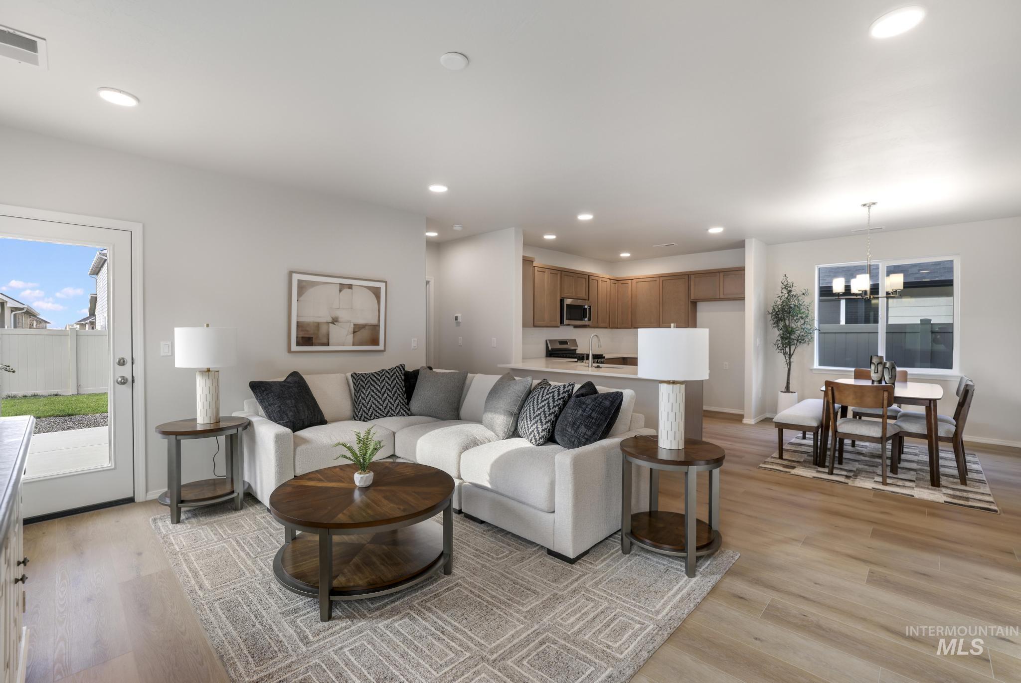 Living room featuring healthy amount of natural light, light wood-style flooring, recessed lighting, and a chandelier