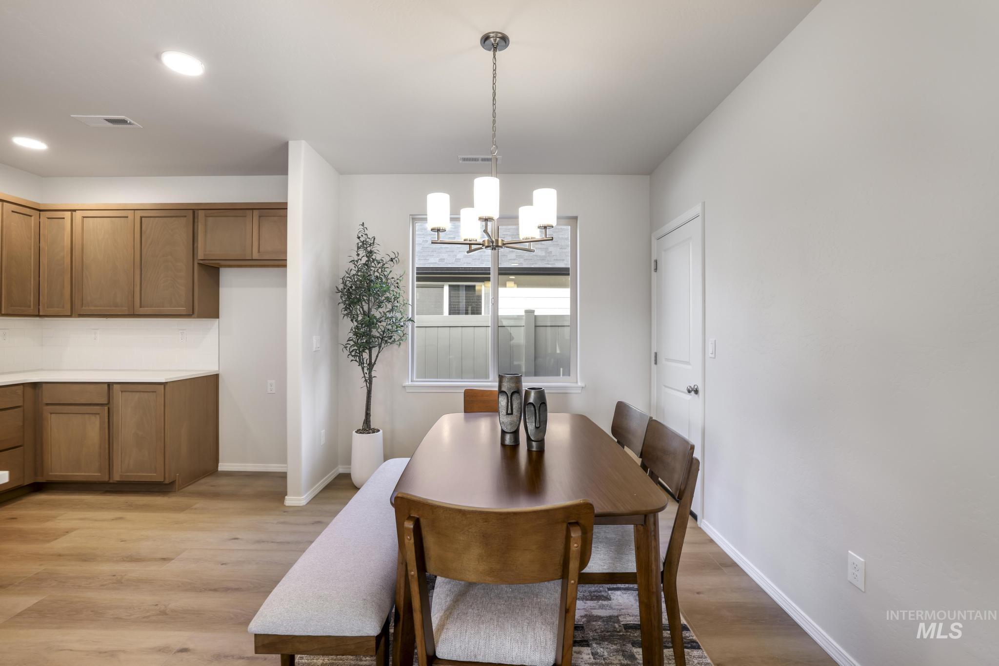 Dining area with light wood finished floors, a chandelier, and recessed lighting