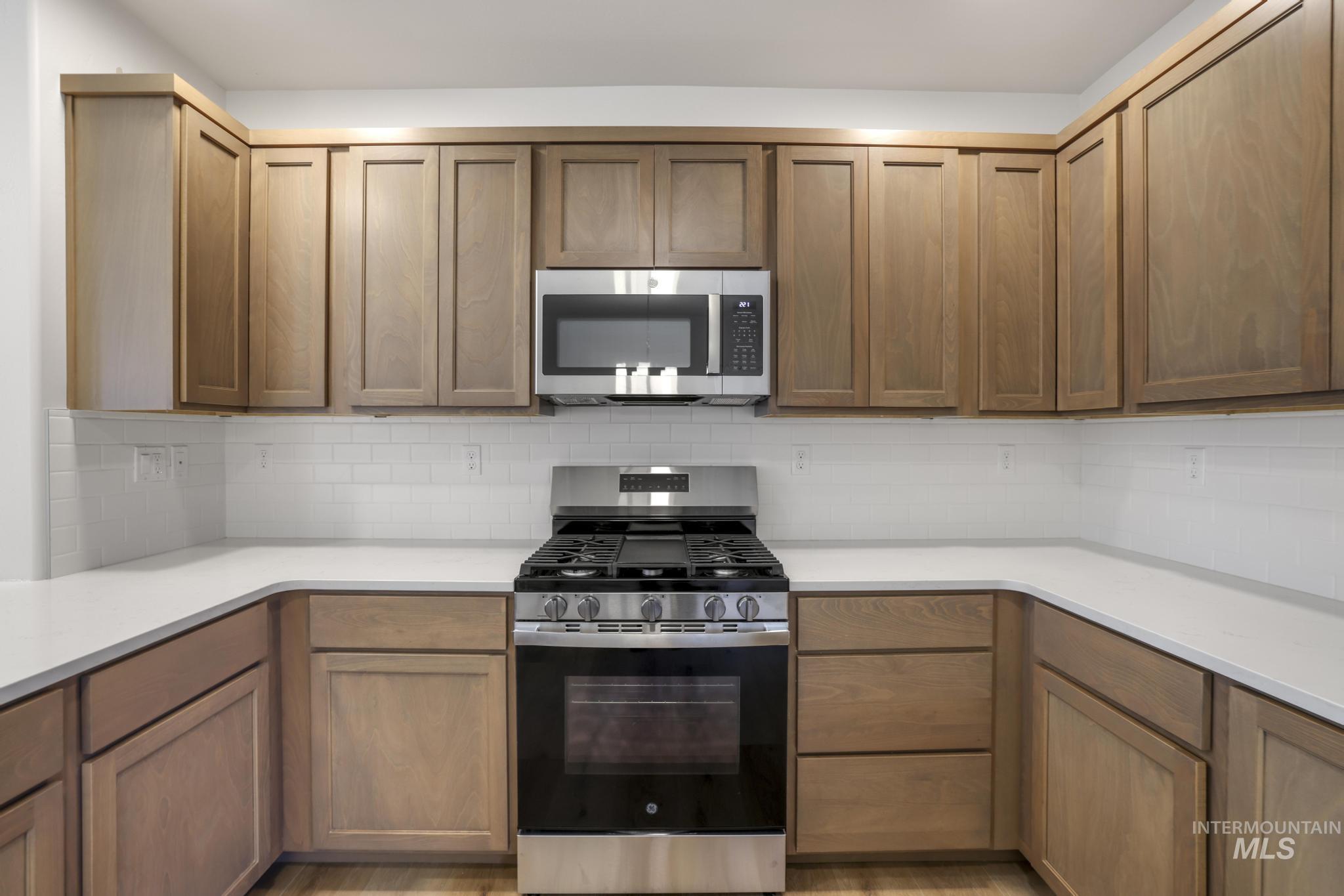 Kitchen featuring appliances with stainless steel finishes, decorative backsplash, and brown cabinetry
