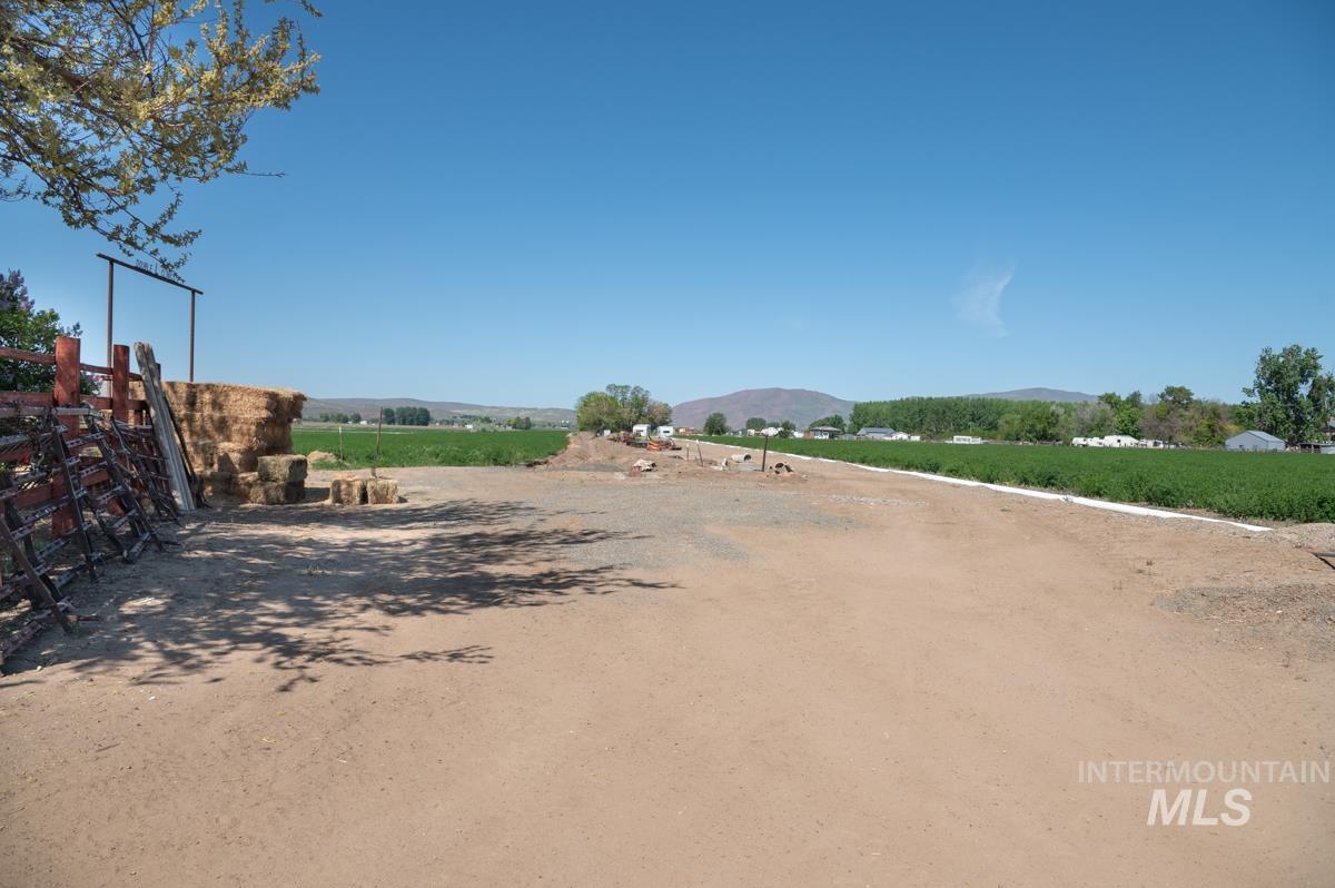 View of dirt / gravel road featuring a view of countryside, agricultural plots, and a mountain view