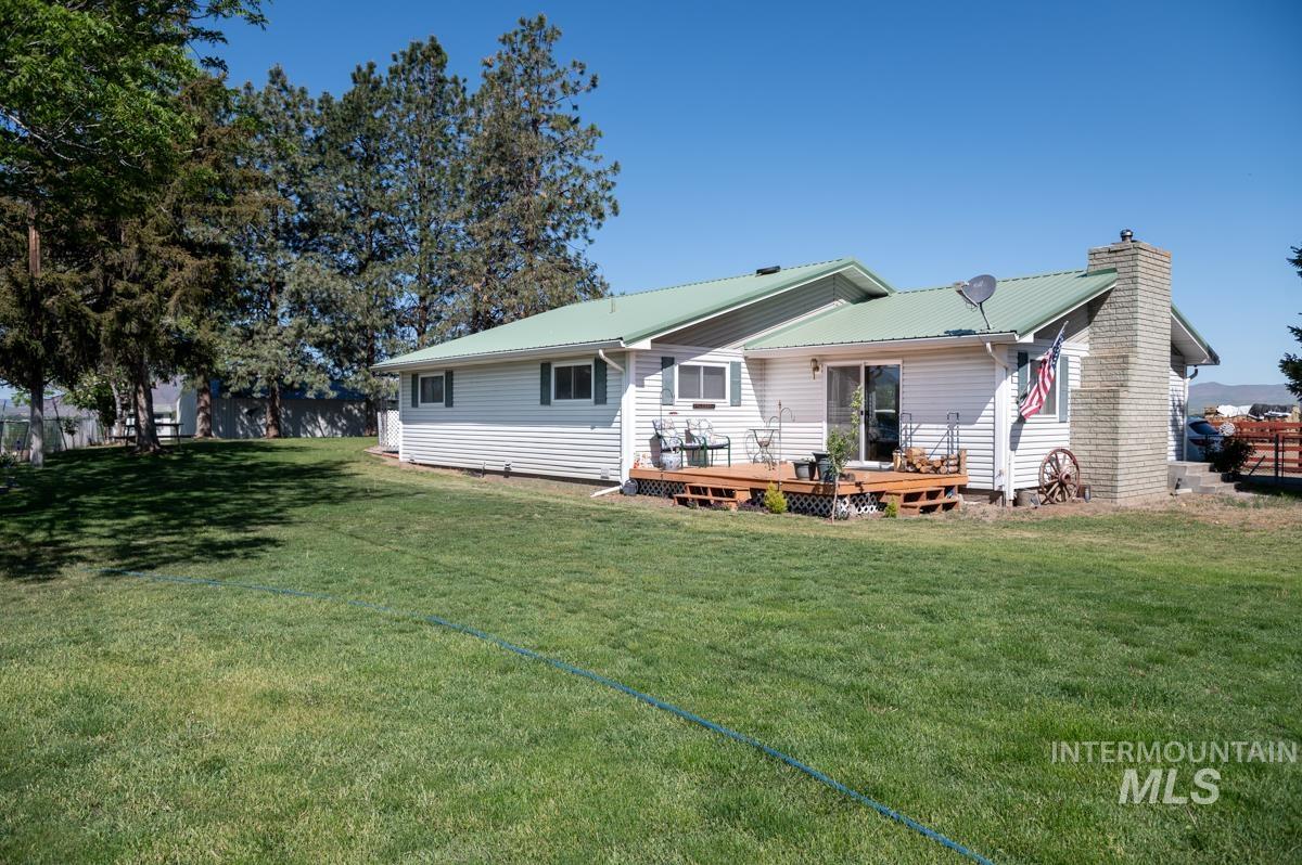 Back of house featuring a wooden deck, a yard, a chimney, and a metal roof