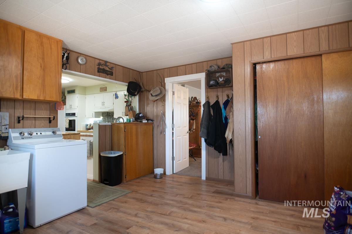 Washroom with washer / dryer, light wood-type flooring, and wooden walls