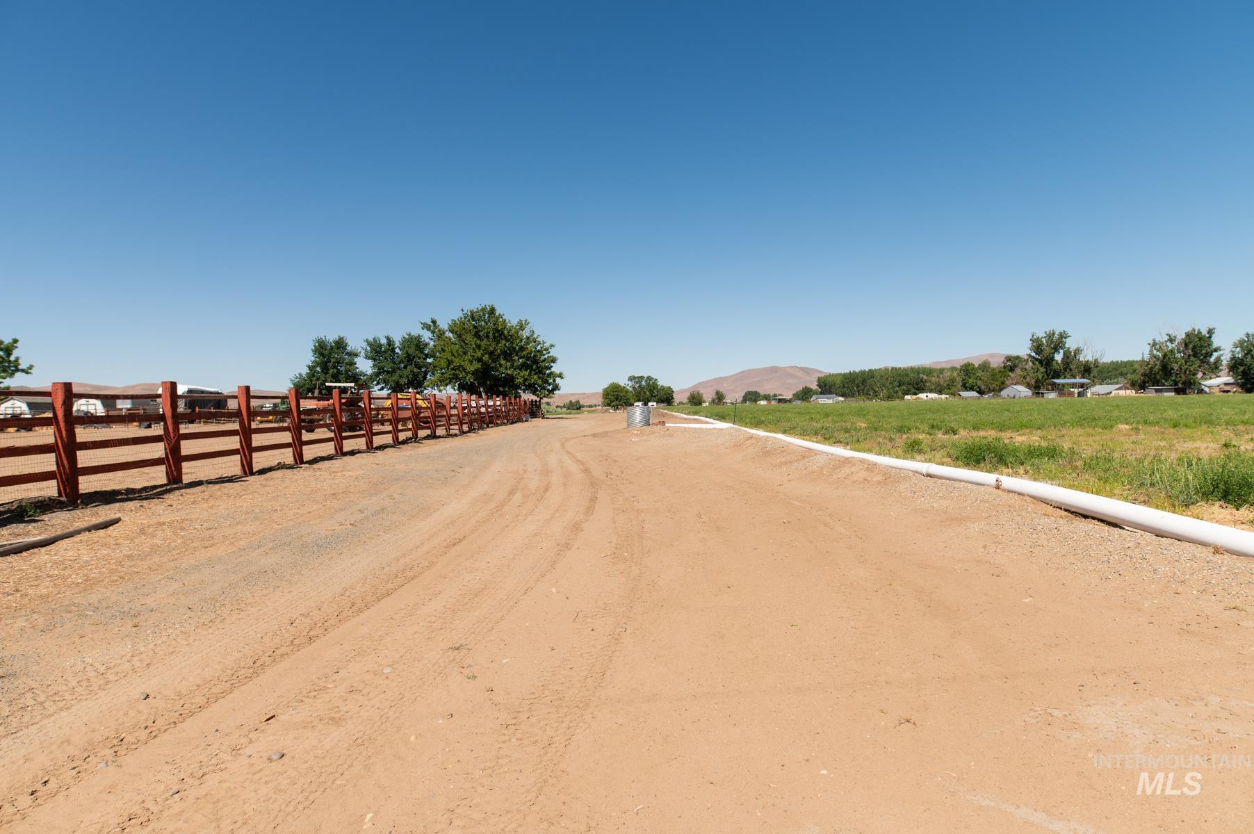 Expansive dirt driveway bordered by a red wood-panel fence