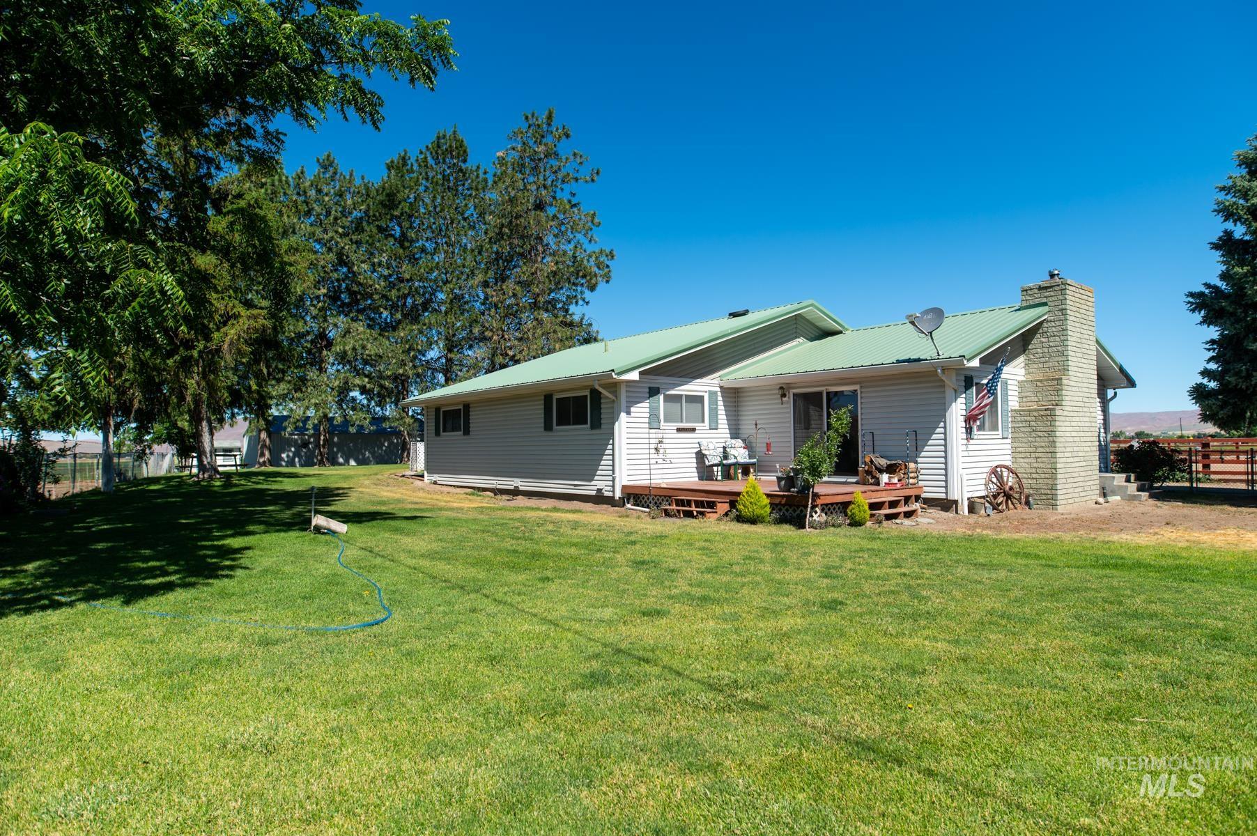 Spacious backyard featuring a manicured lawn, mature trees, and a multi-level wood deck