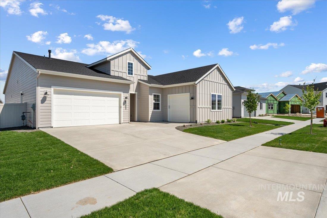 View of front facade with board and batten siding, a front lawn, an attached garage, driveway, and a shingled roof