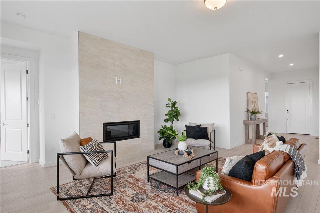 Living room with a tile fireplace, light wood-style flooring, and recessed lighting