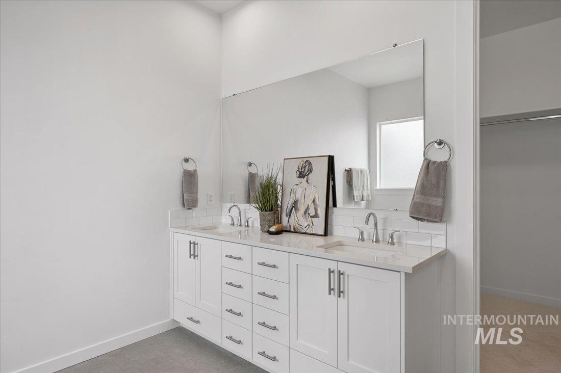 Full bath featuring double vanity and baseboards