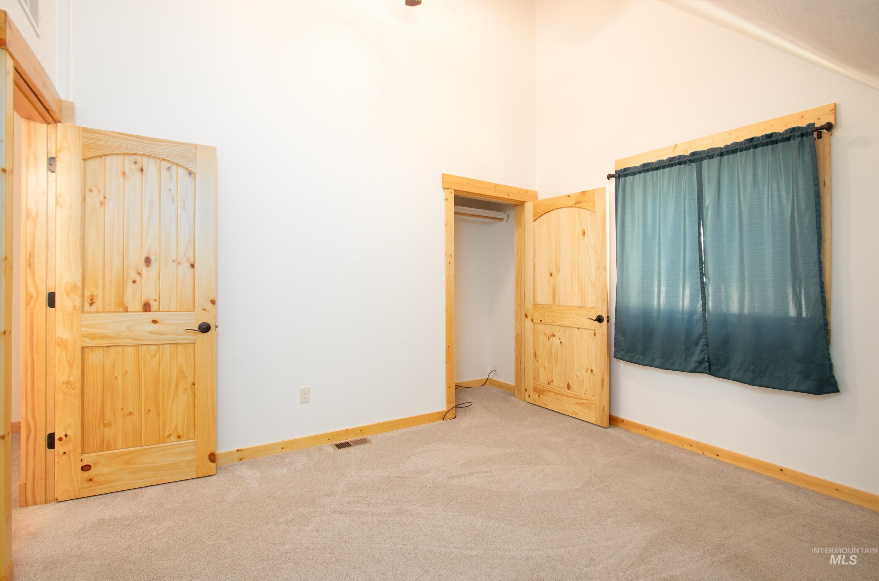 Unfurnished bedroom featuring carpet flooring and lofted ceiling