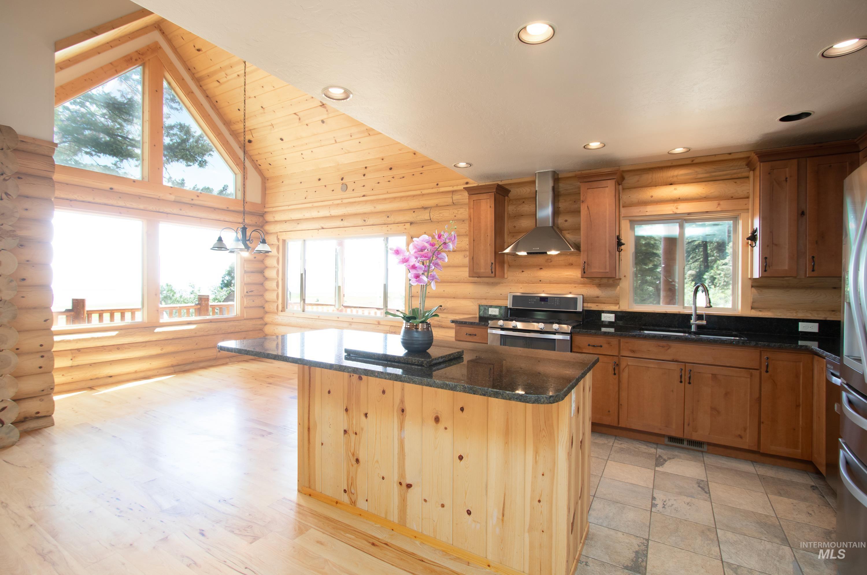 Kitchen with a kitchen island, stainless steel appliances, dark stone counters, vaulted ceiling, and wood finish cabinets
