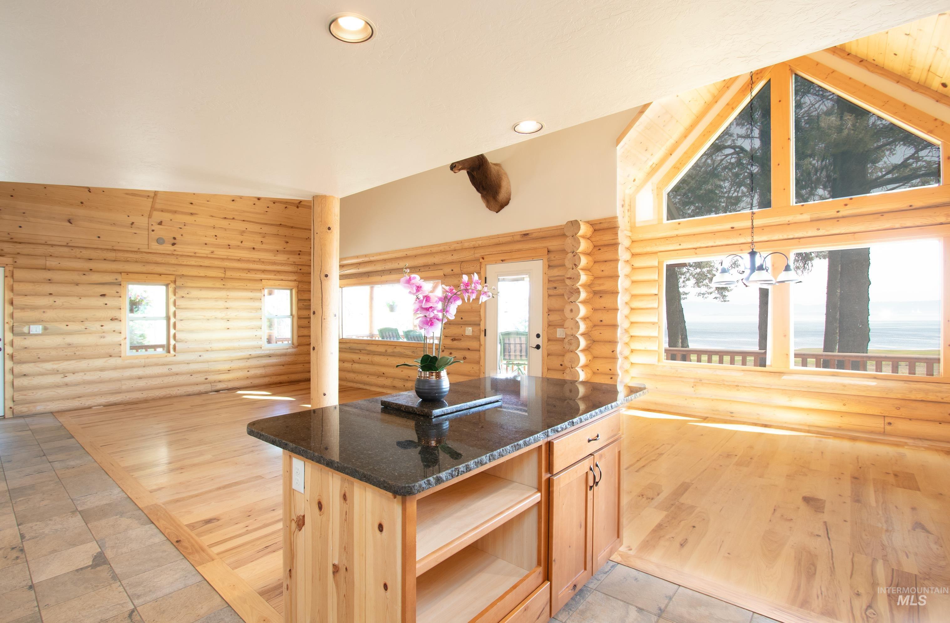 Kitchen with log walls, light wood finish cabinets, light wood-style floors, dark stone countertops, and recessed lighting