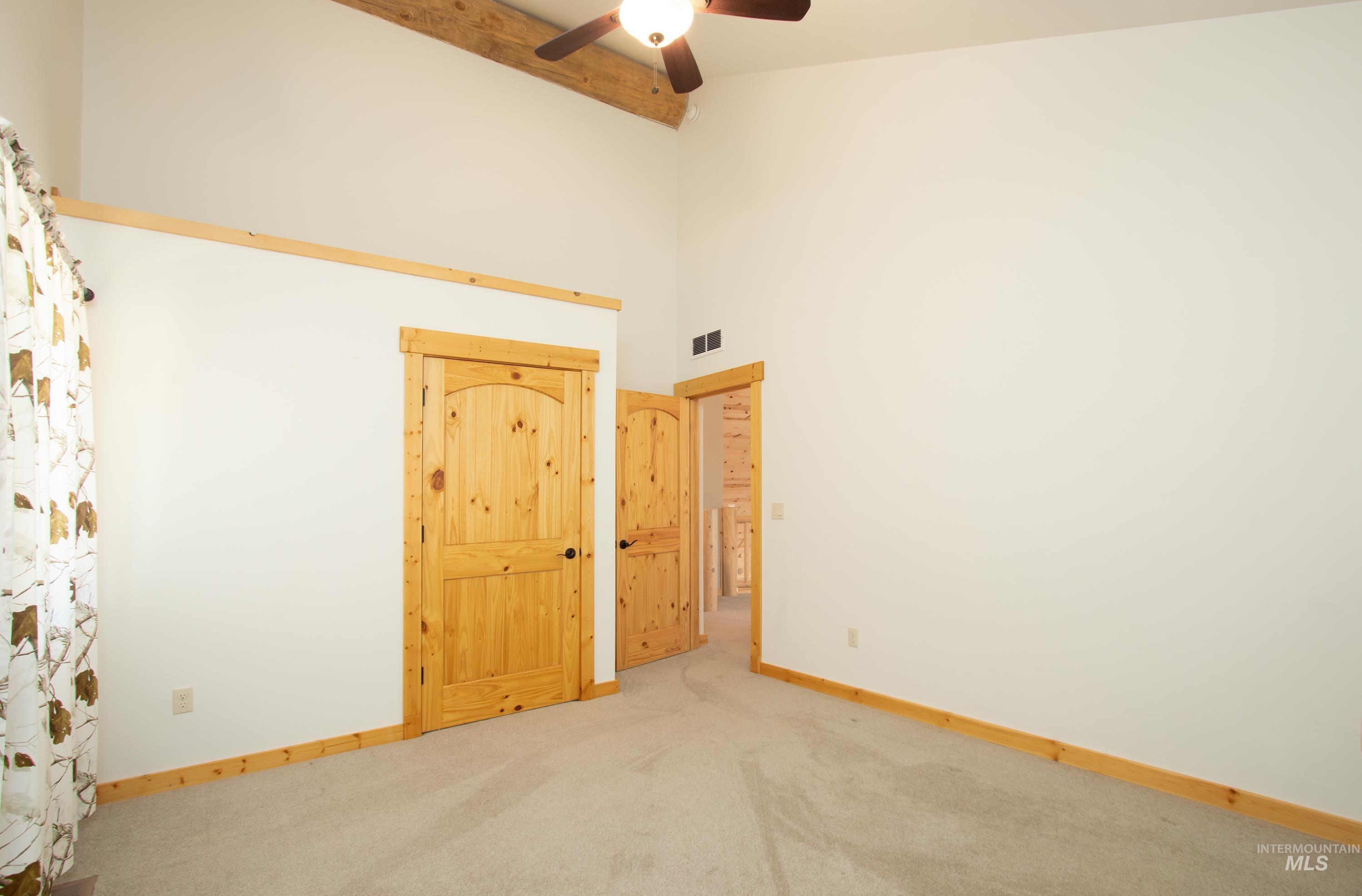 Spare room with a high ceiling, light carpet, and a ceiling fan