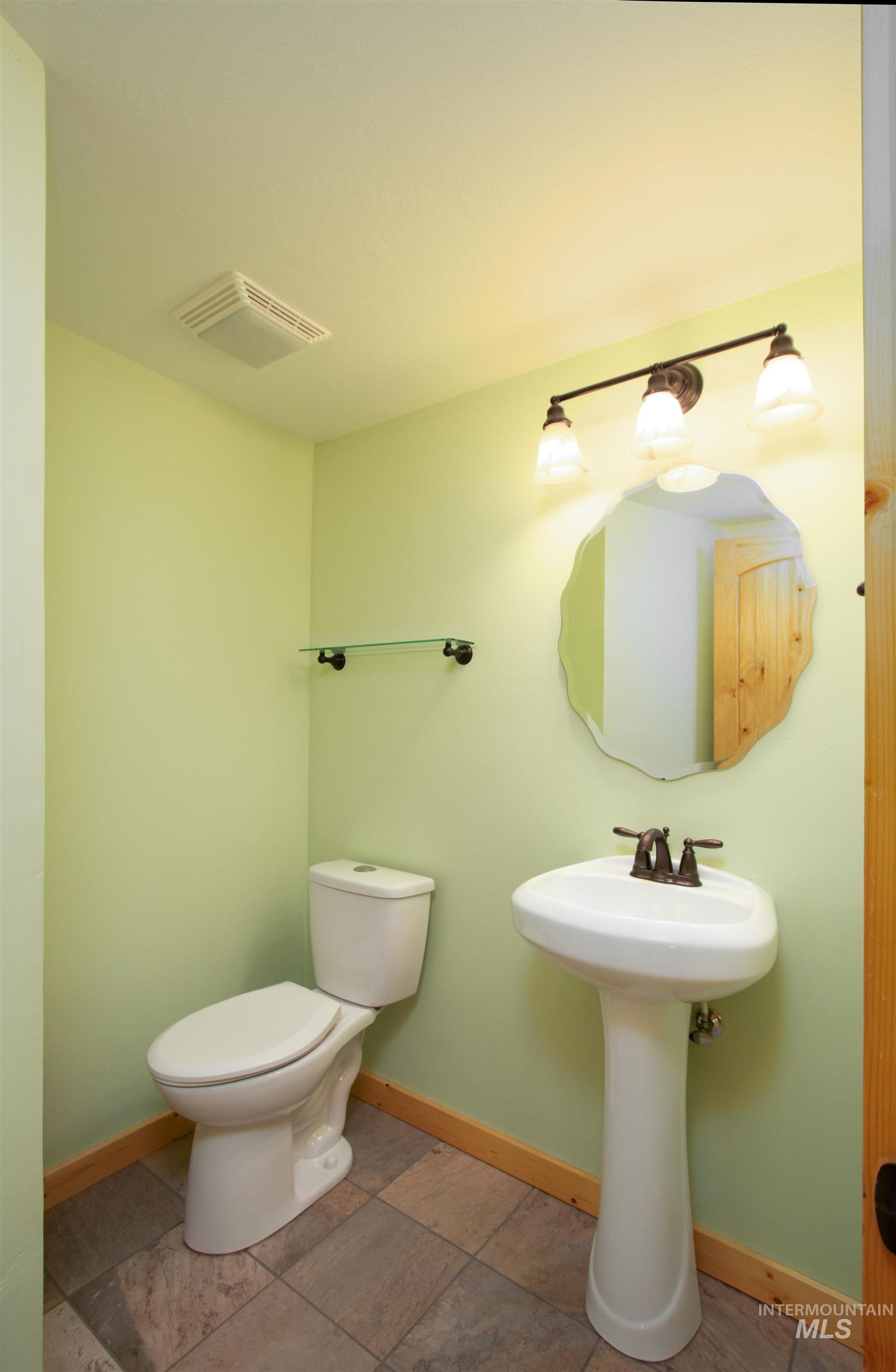 Half bathroom with baseboards and stone finish flooring