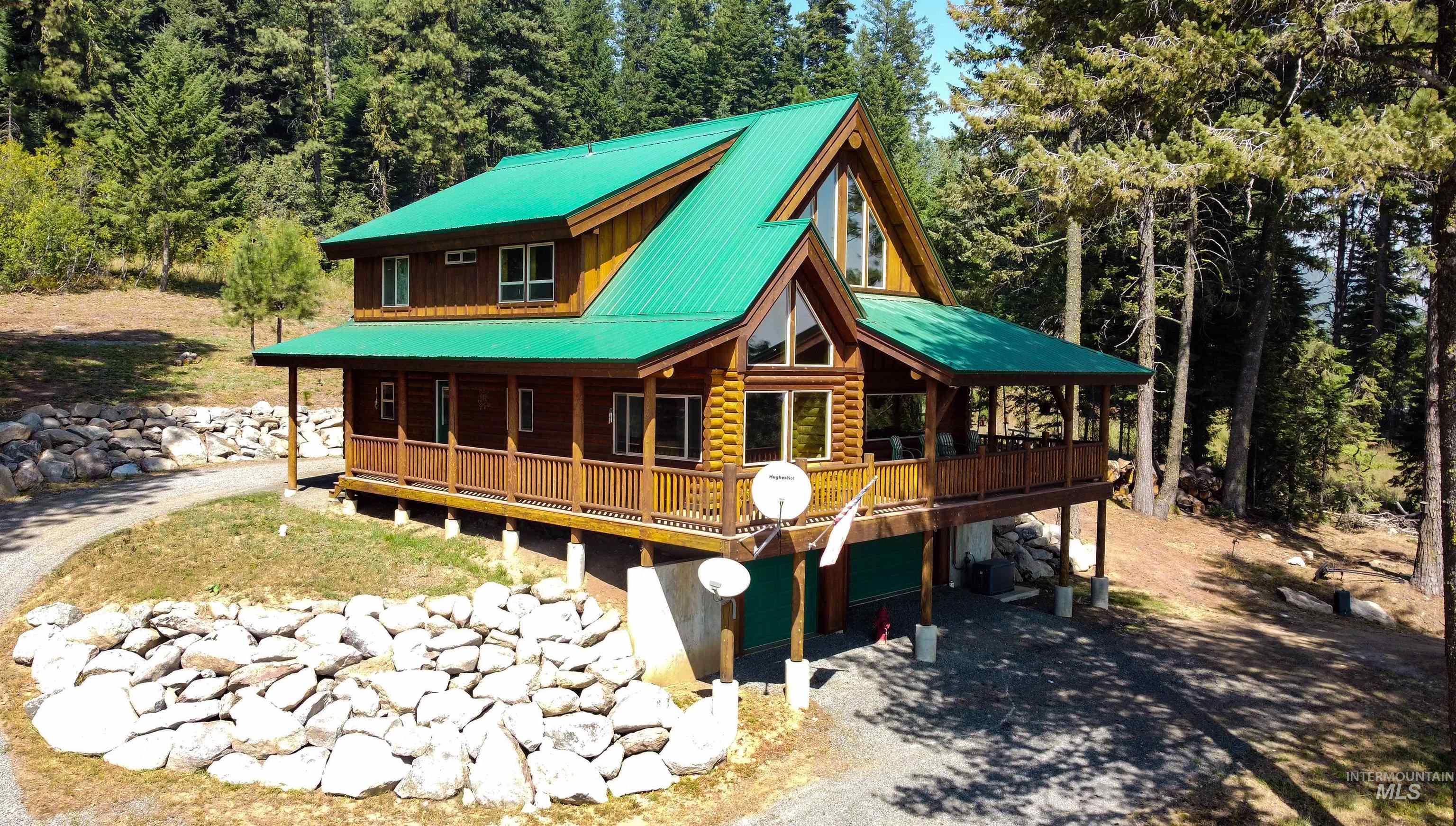 Rear view of property with a porch, driveway, an attached garage, and a metal roof
