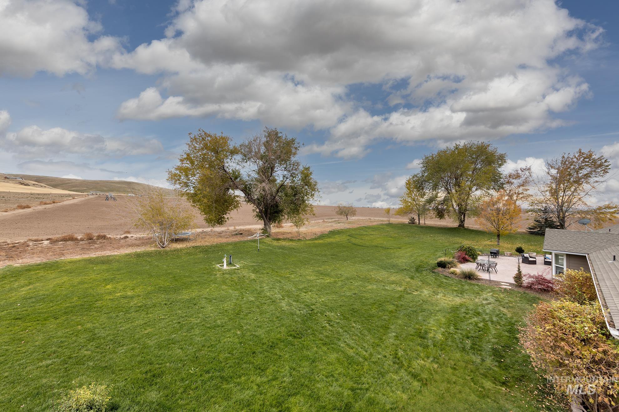 View of grassy yard with a rural view and a patio