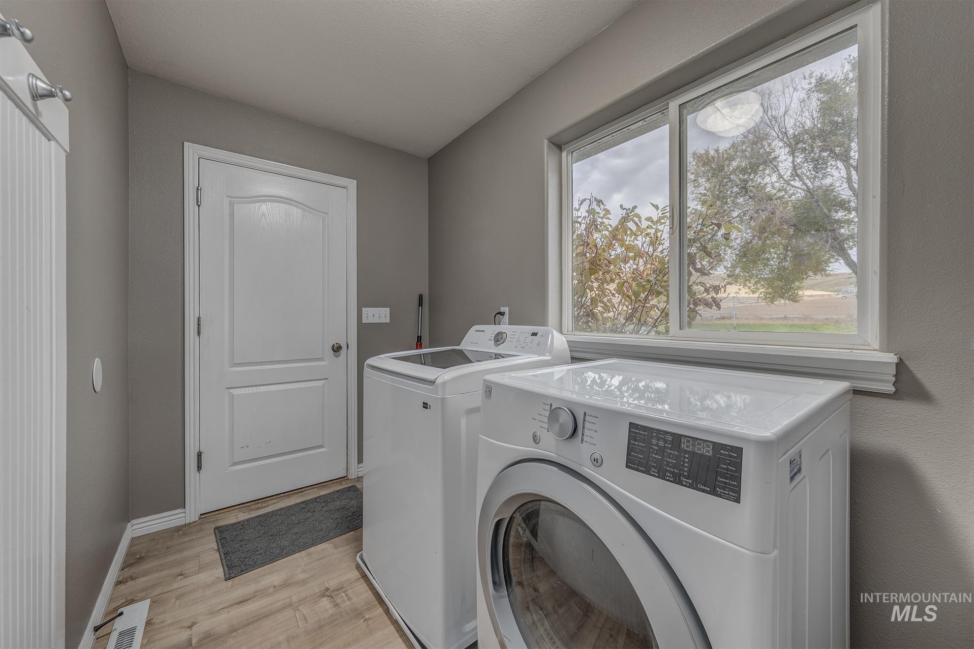 Laundry room featuring light wood finished floors and separate washer and dryer