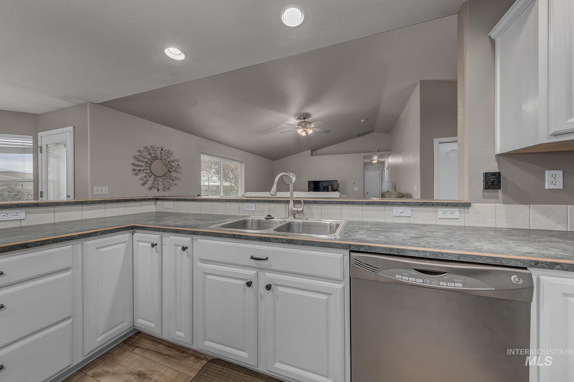Kitchen featuring white cabinetry, stainless steel dishwasher, lofted ceiling, a ceiling fan, and recessed lighting