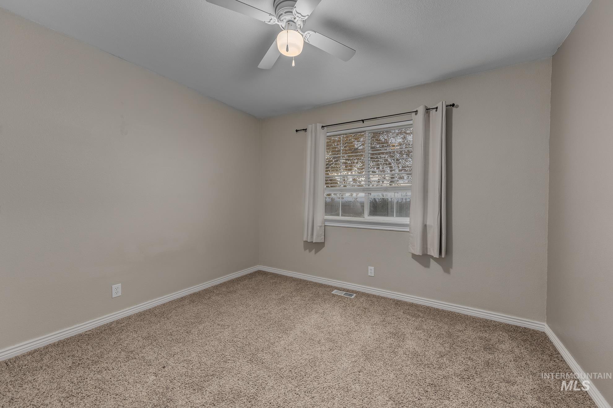 Empty room with carpet floors and ceiling fan