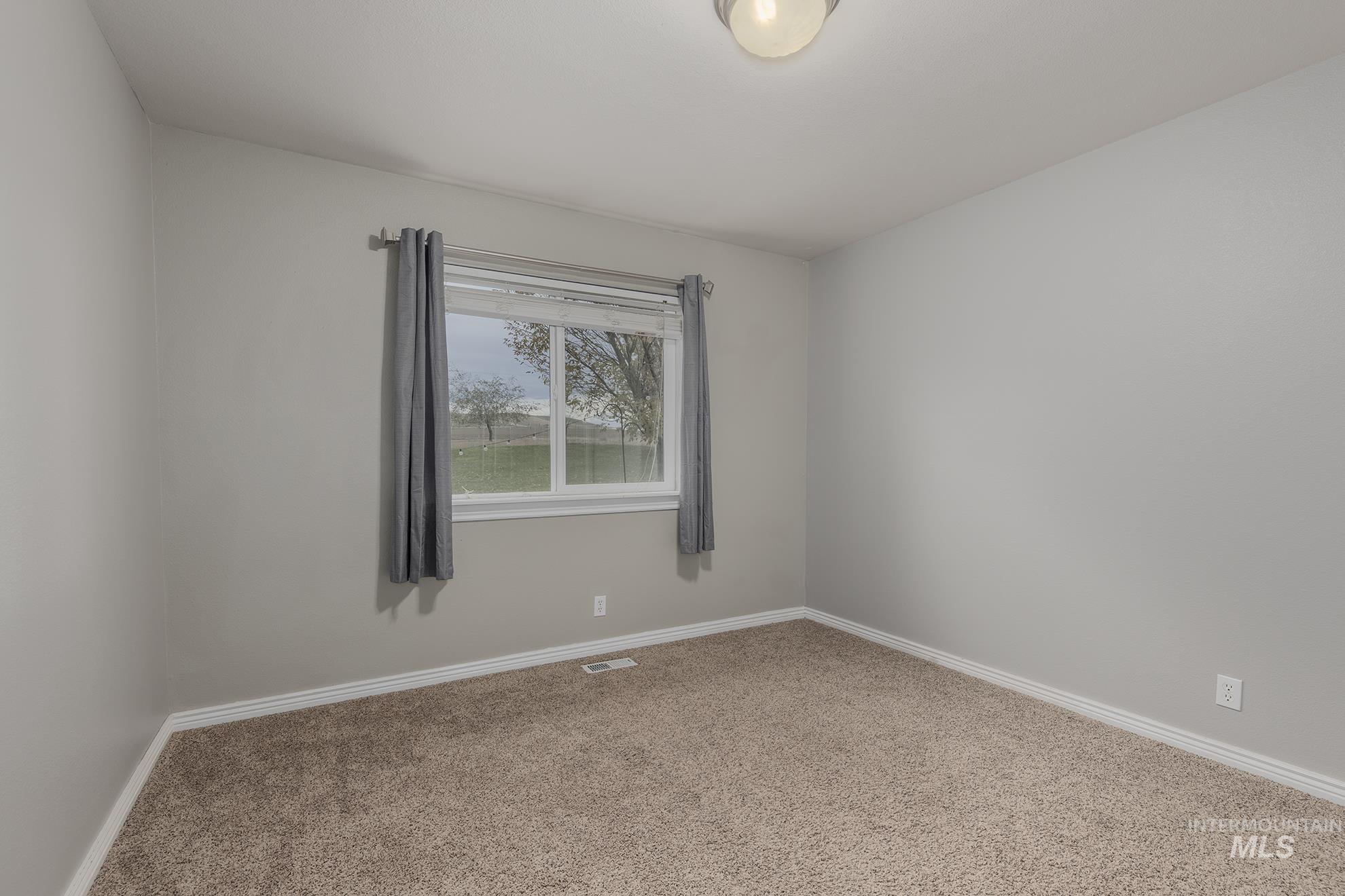 Spare room featuring carpet floors and baseboards