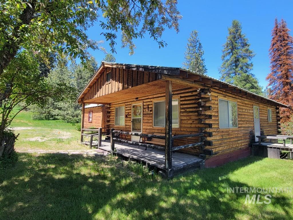 Rear view of property featuring log siding, a yard, and a deck