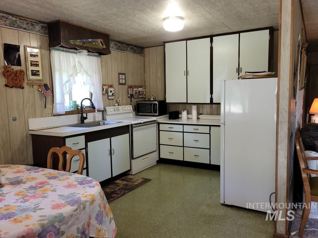 Kitchen with white appliances, light countertops, and white cabinetry