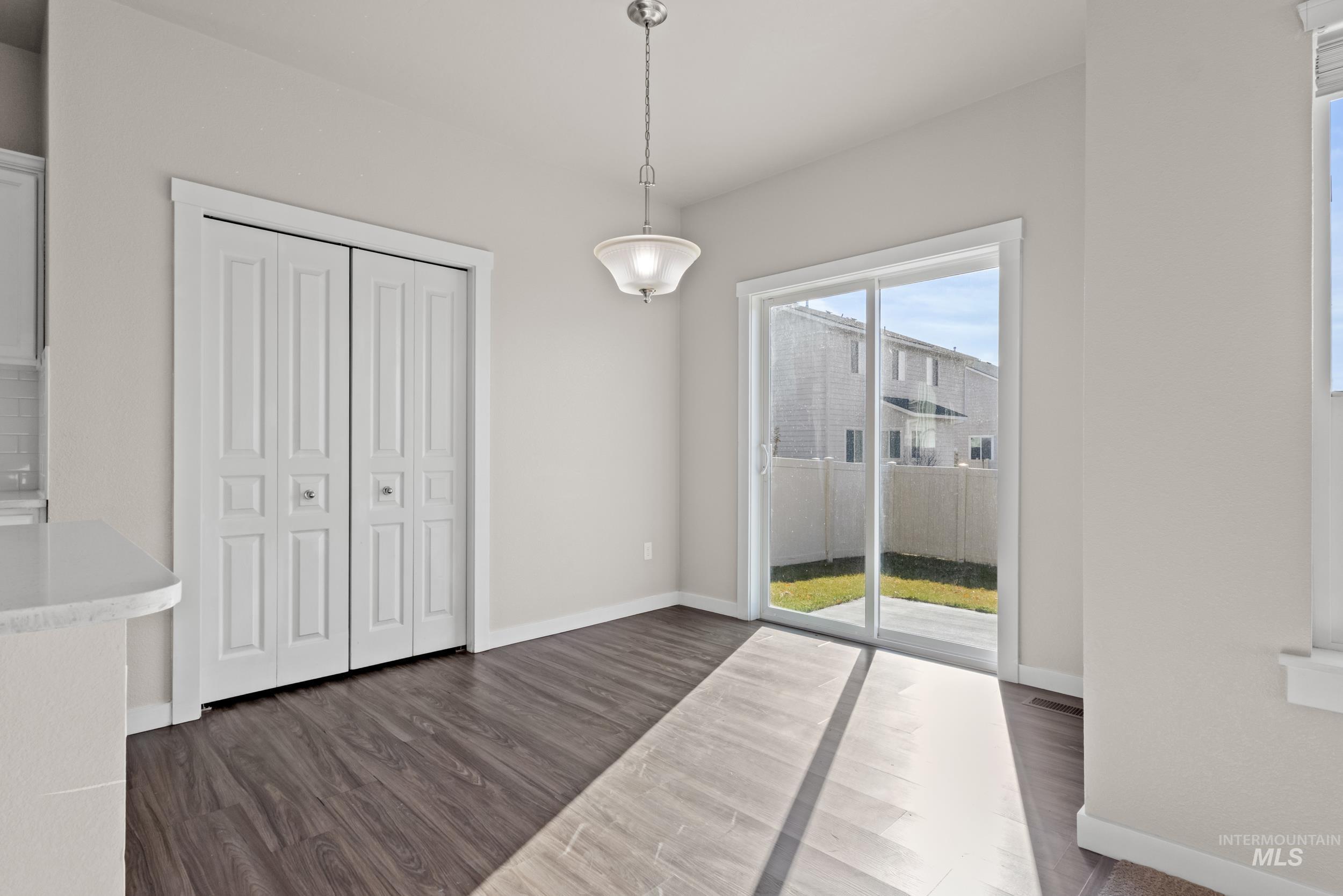 Unfurnished dining area featuring dark wood-style flooring and baseboards
