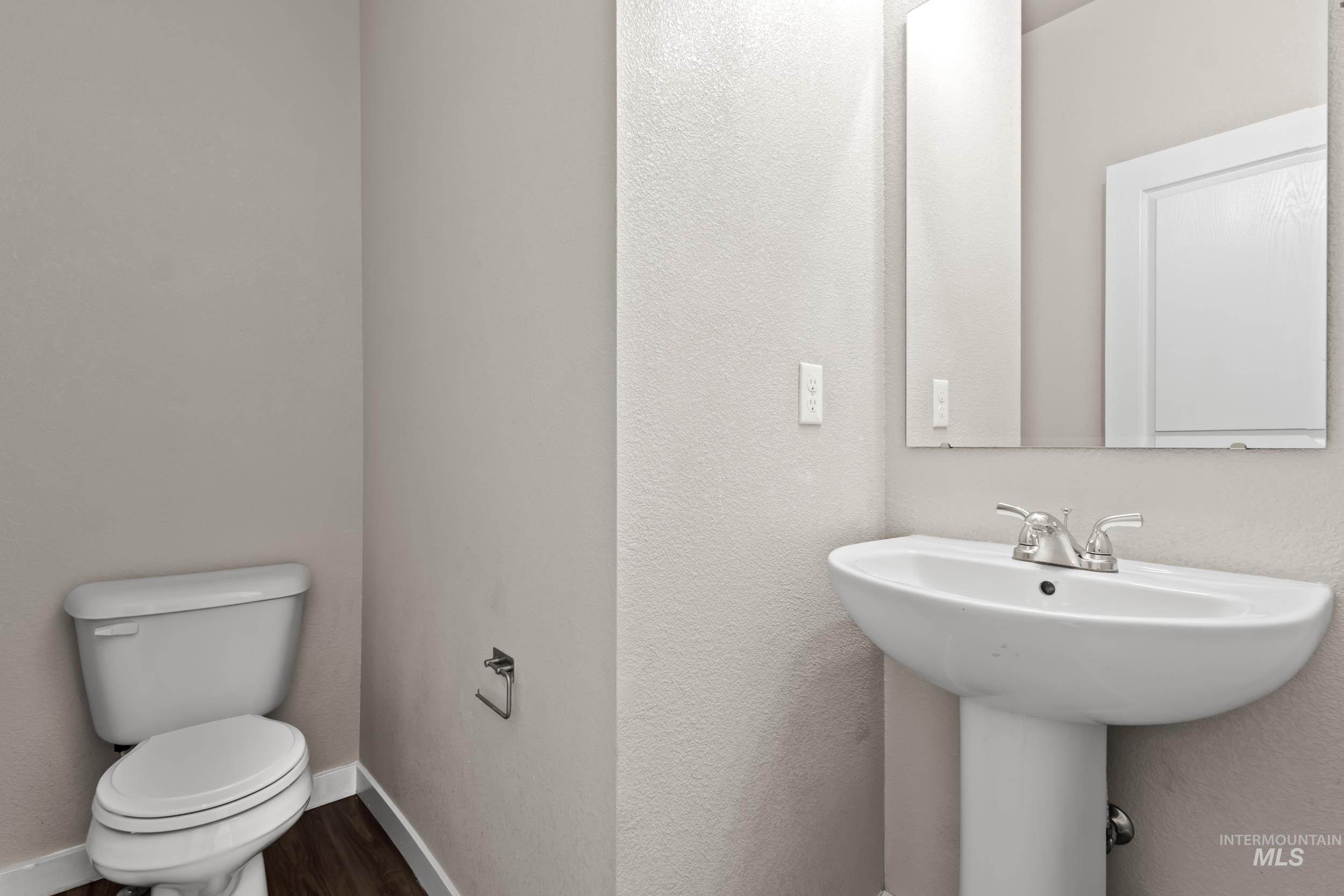 Bathroom featuring a textured wall and dark wood-style flooring