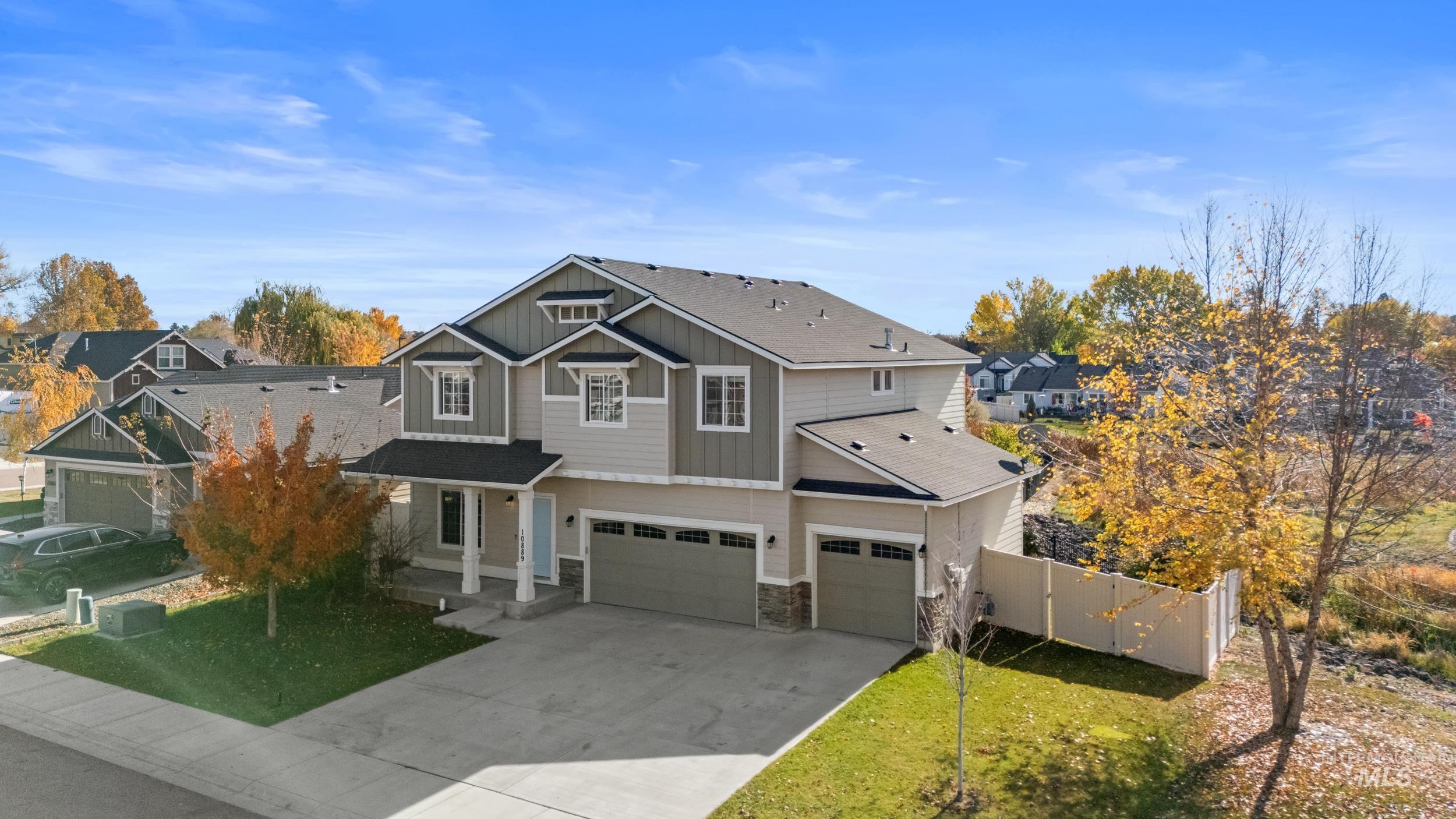 Craftsman house with an attached garage, board and batten siding, driveway, stone siding, and roof with shingles