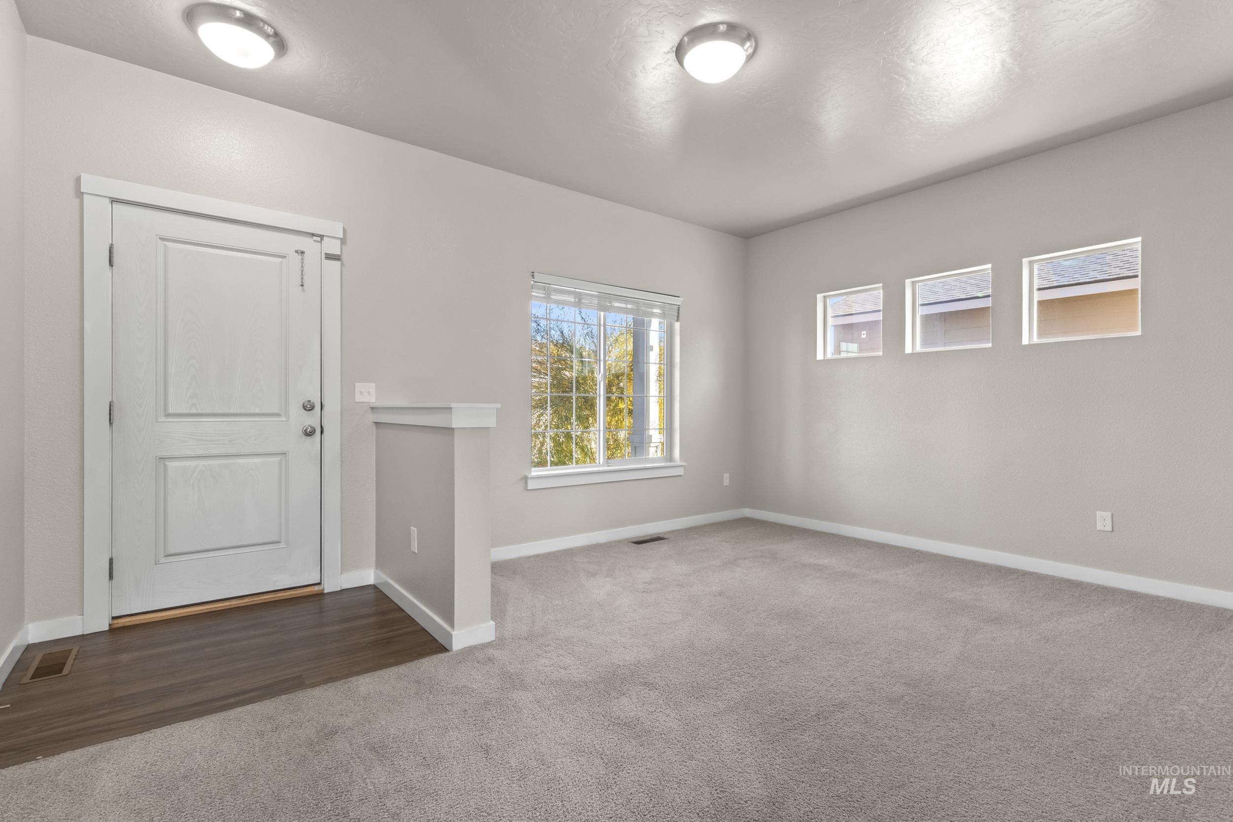 Spare room featuring dark carpet and baseboards