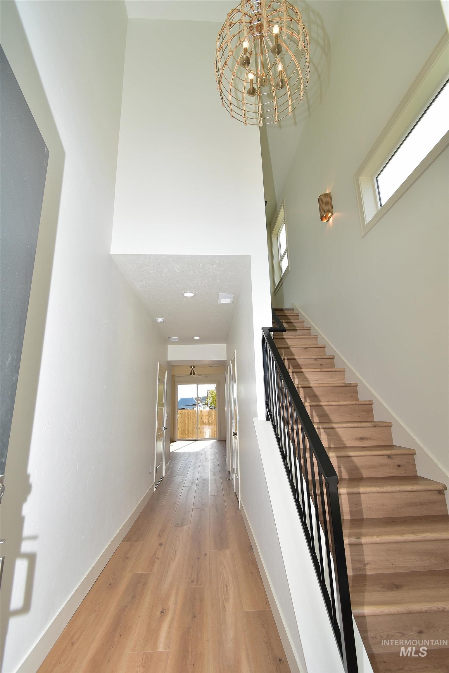 Stairway with a chandelier, a high ceiling, and wood finished floors