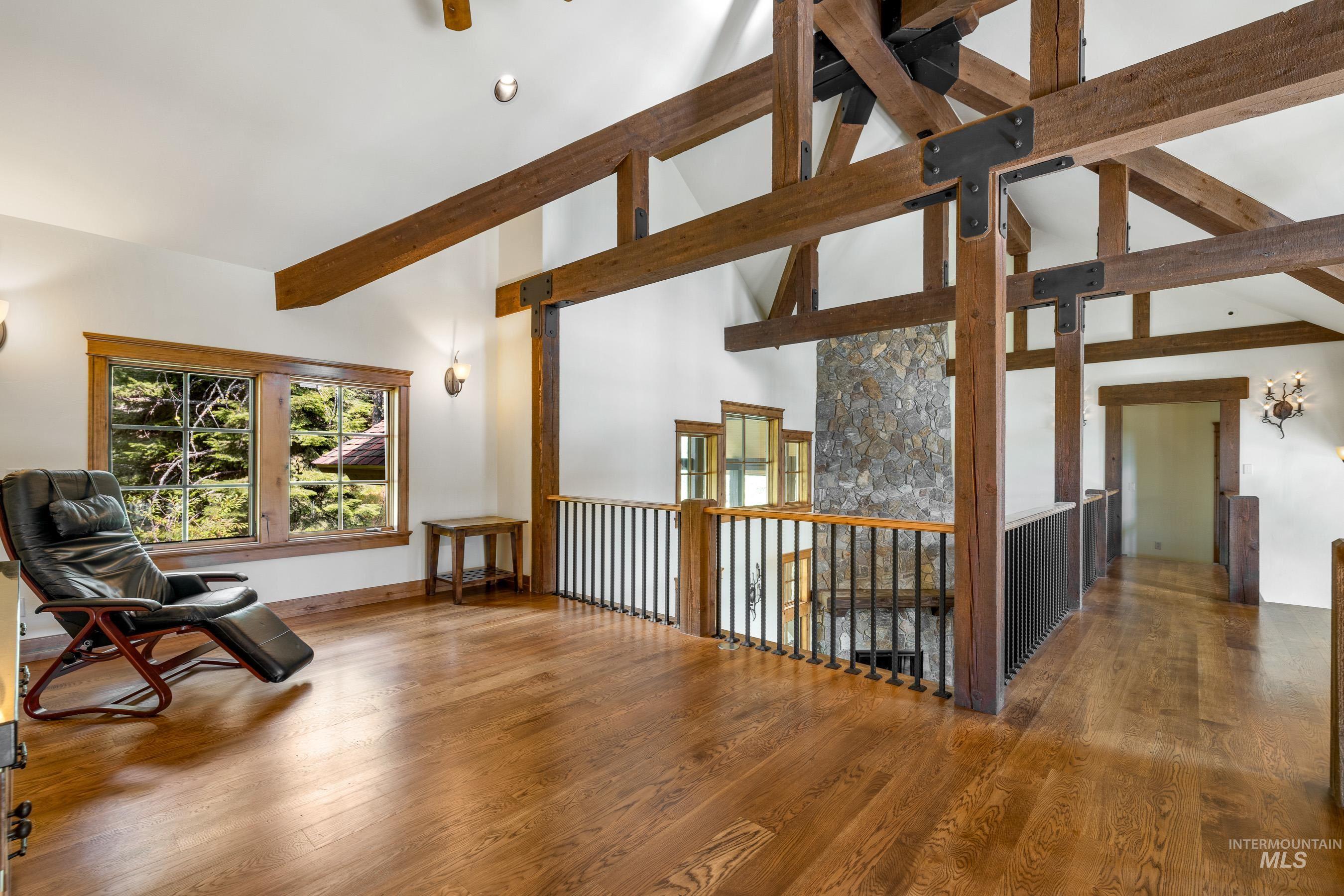 Living area with high vaulted ceiling, wood finished floors, and beam ceiling