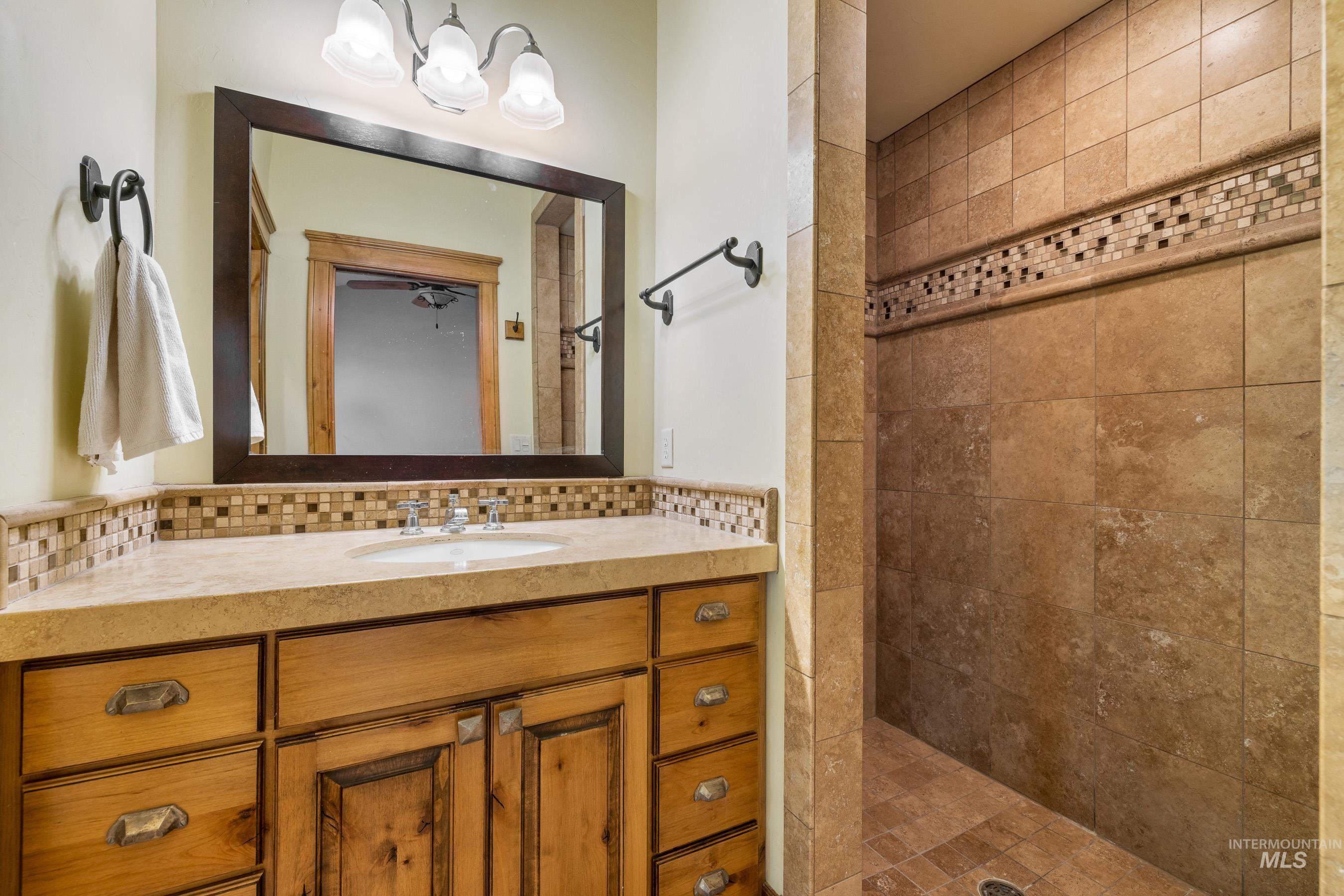 Bathroom featuring vanity, a shower stall, and decorative backsplash