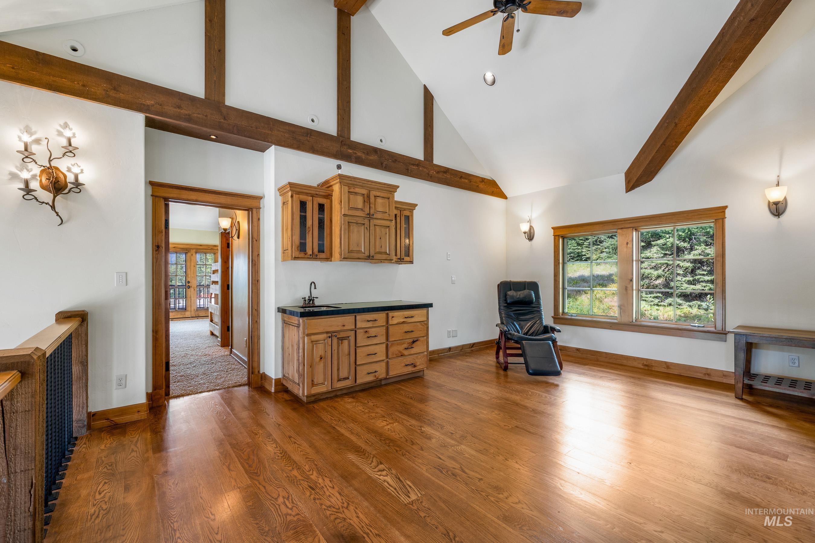 Unfurnished living room featuring high vaulted ceiling, wood finished floors, plenty of natural light, beamed ceiling, and ceiling fan