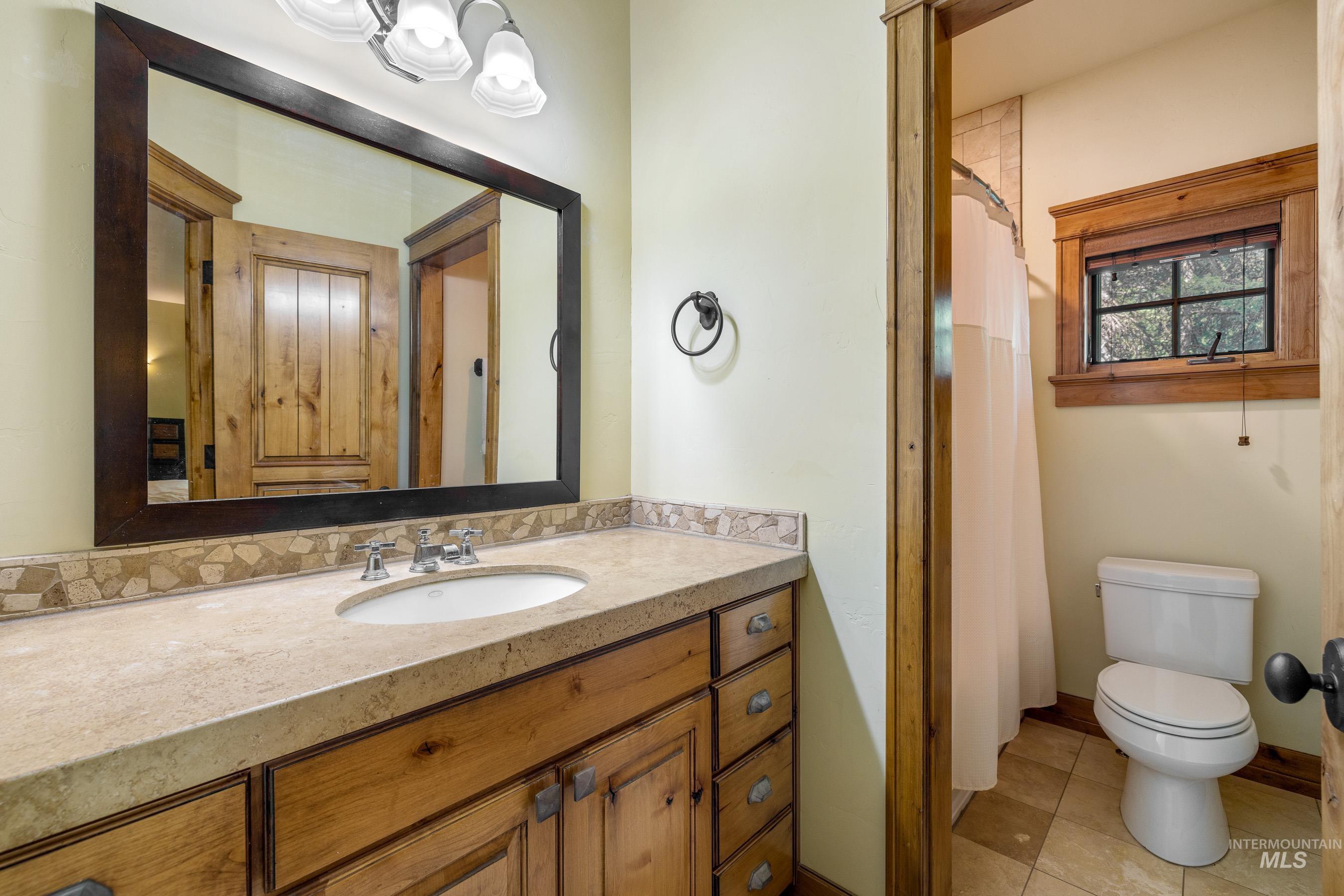 Full bath with vanity, light tile patterned floors, and curtained shower