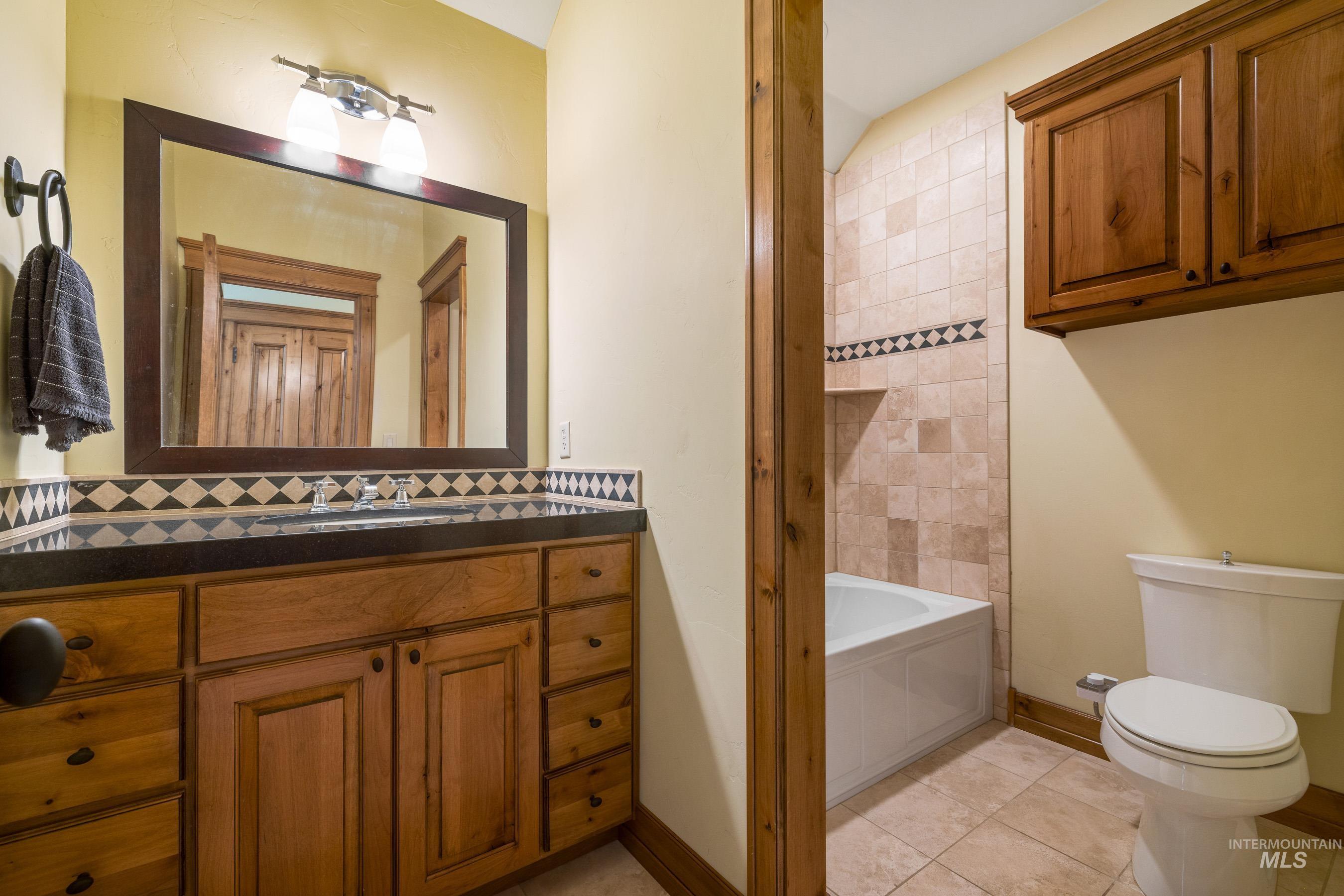 Full bathroom with decorative backsplash, vanity, light tile patterned floors, and bathtub / shower combination