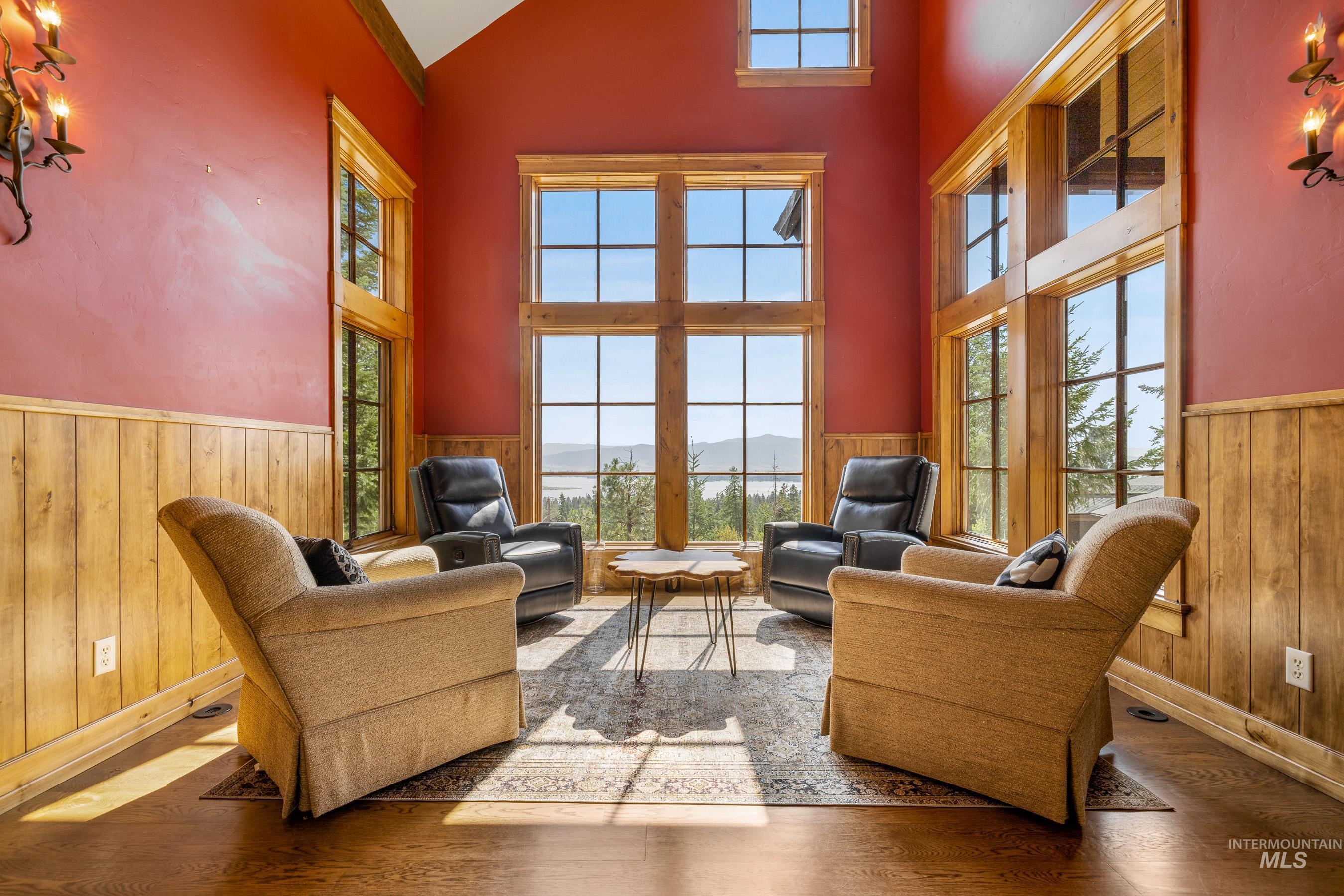Sitting room with a mountain view, a wainscoted wall, wooden walls, wood finished floors, and high vaulted ceiling