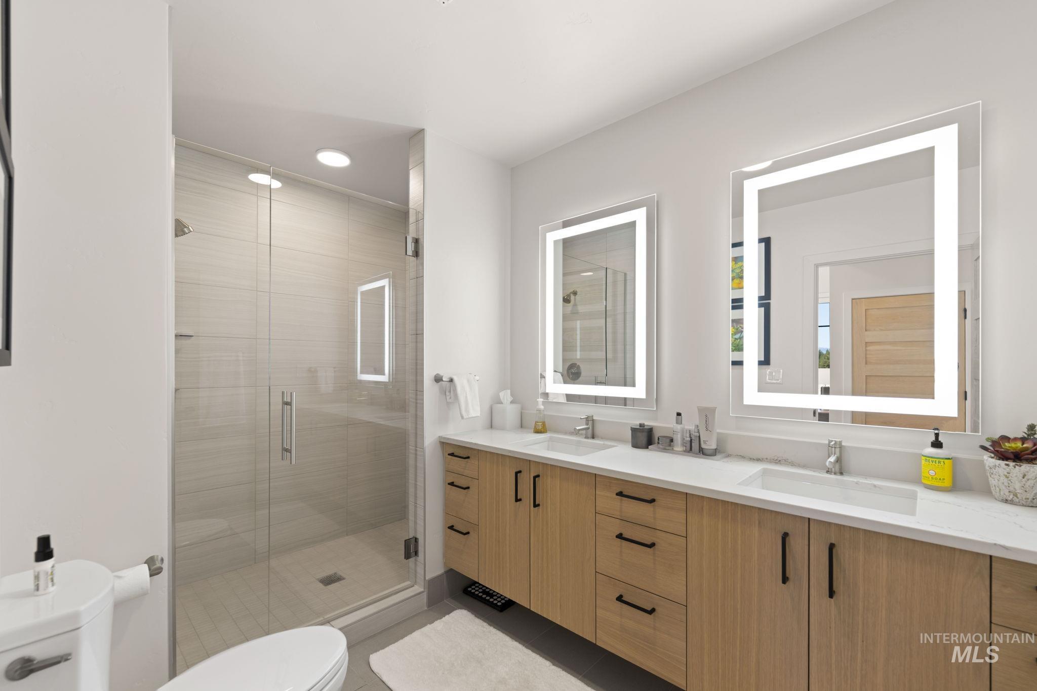 Full bath with double vanity, a shower stall, recessed lighting, and light tile patterned floors