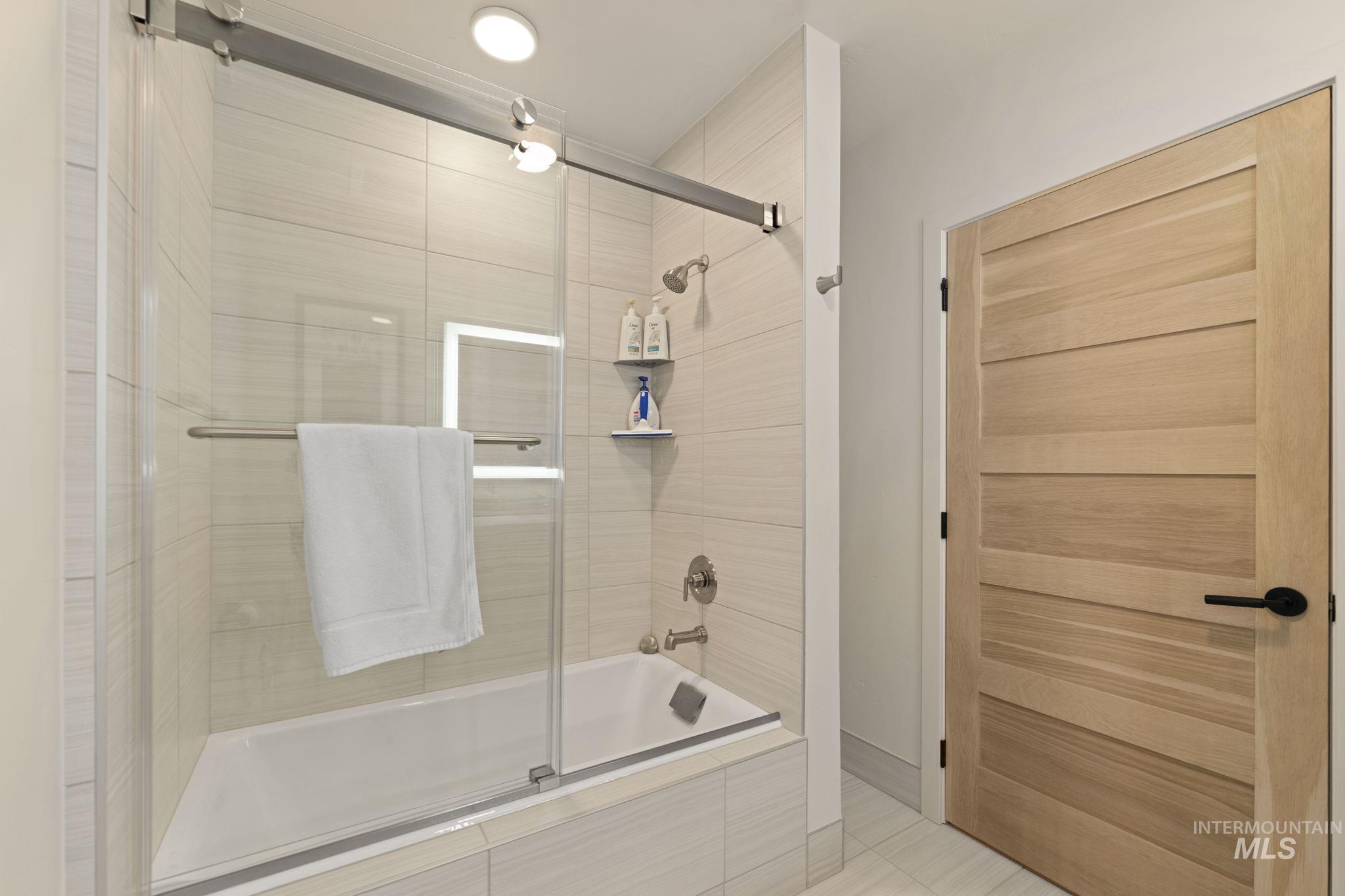 Full bath featuring tiled shower / bath and light tile patterned flooring