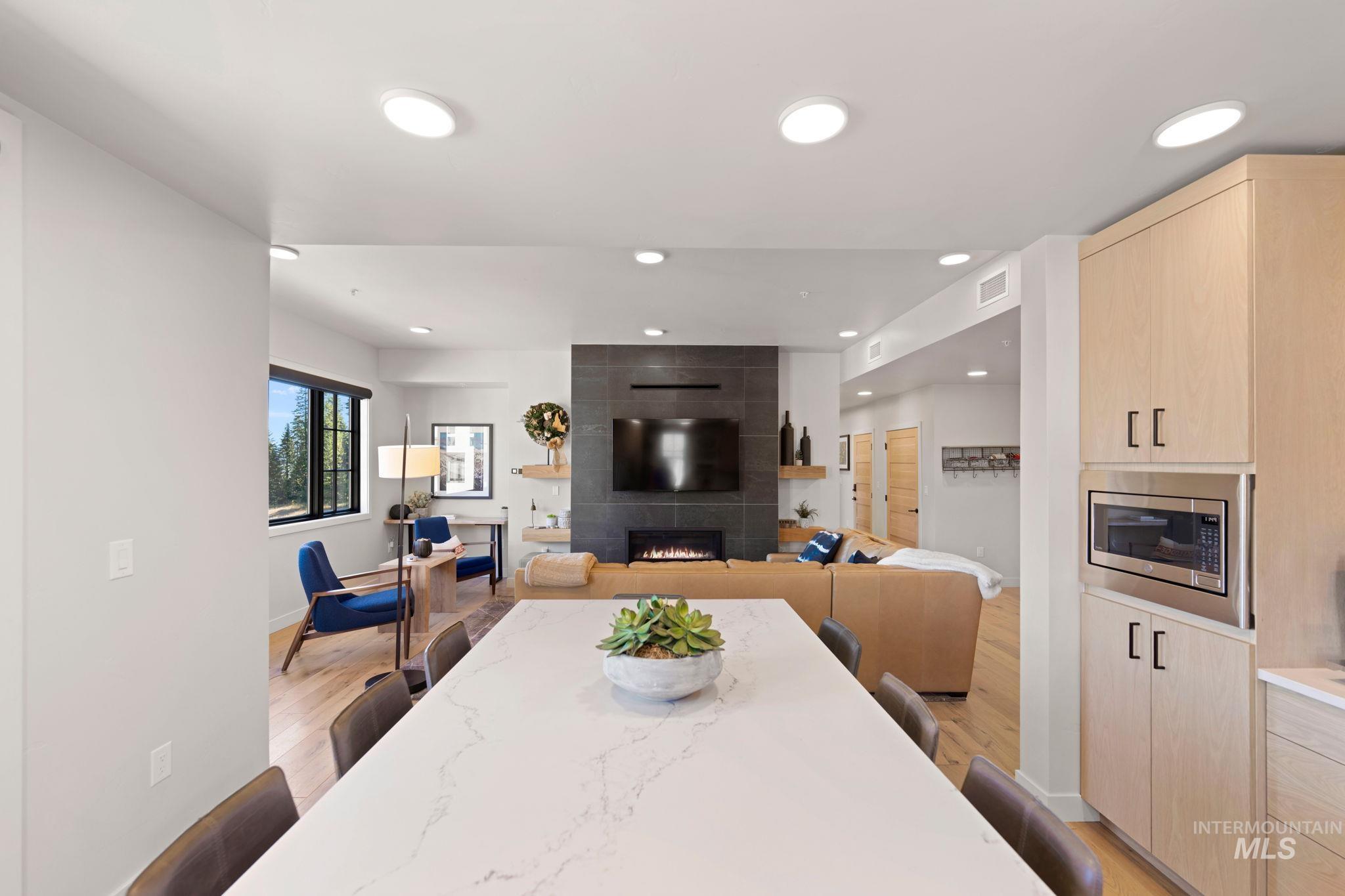 Dining space with light wood-style floors, a fireplace, and recessed lighting