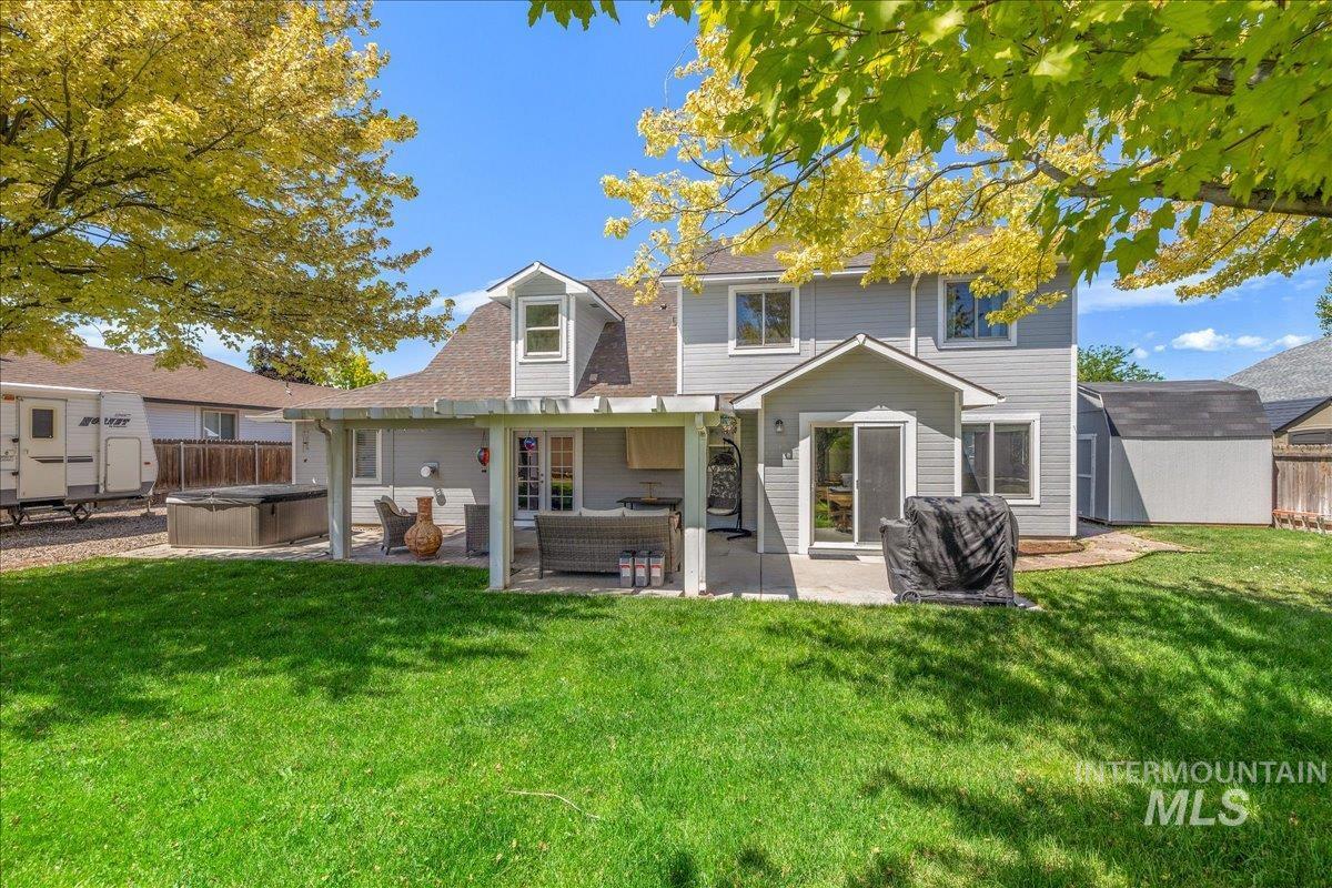 Expansive backyard featuring a spacious covered patio, hot tub, and detached storage shed