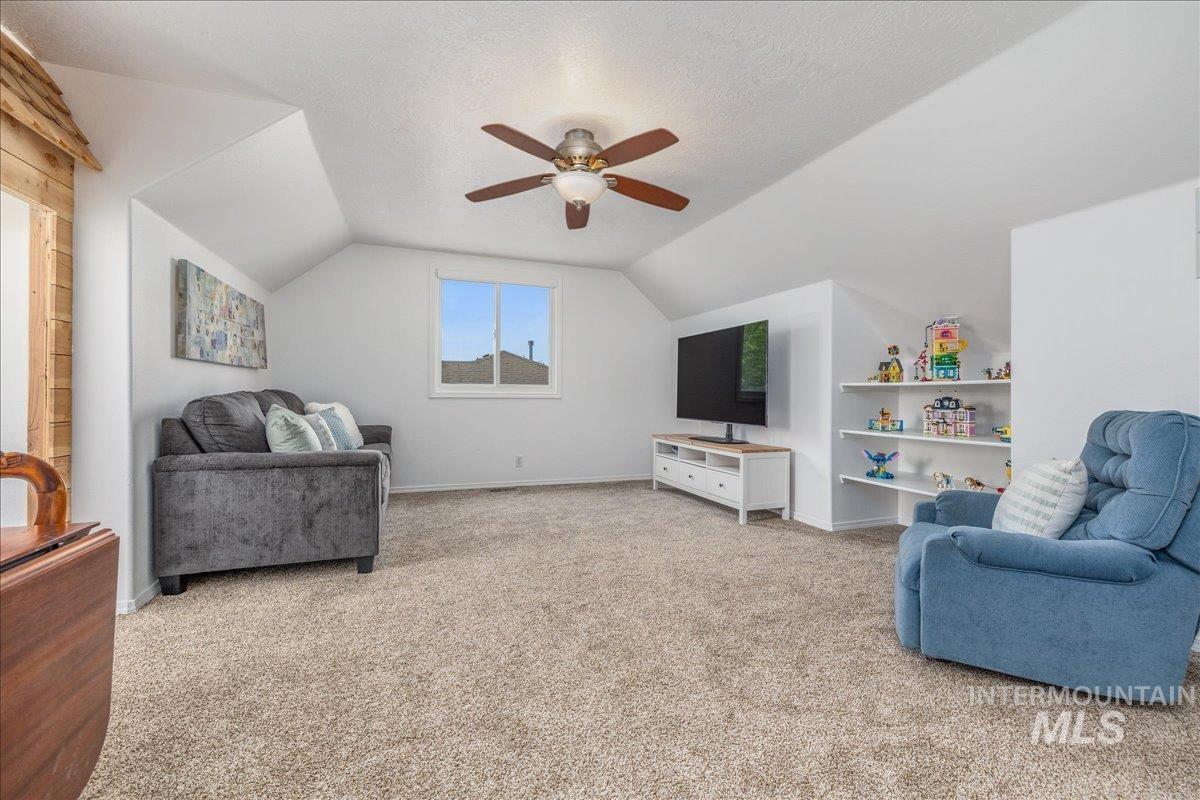 Carpeted room featuring a ceiling fan, sloped ceilings, and a double window