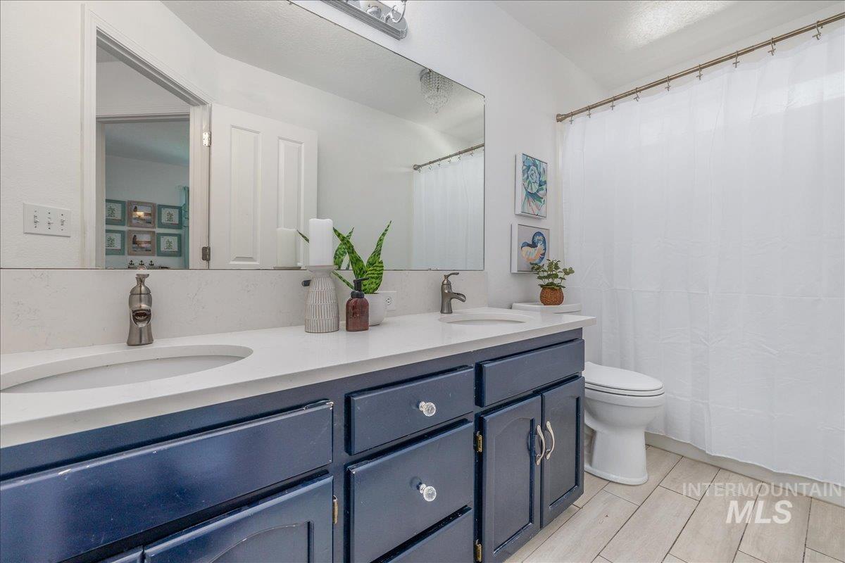 Bathroom featuring a dual vanity with a light-toned countertop, deep blue cabinetry, and brushed nickel faucets
