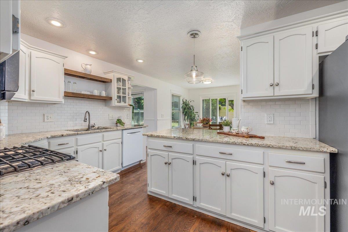 Kitchen featuring white cabinetry, granite countertops, a subway tile backsplash, and wood-finish flooring